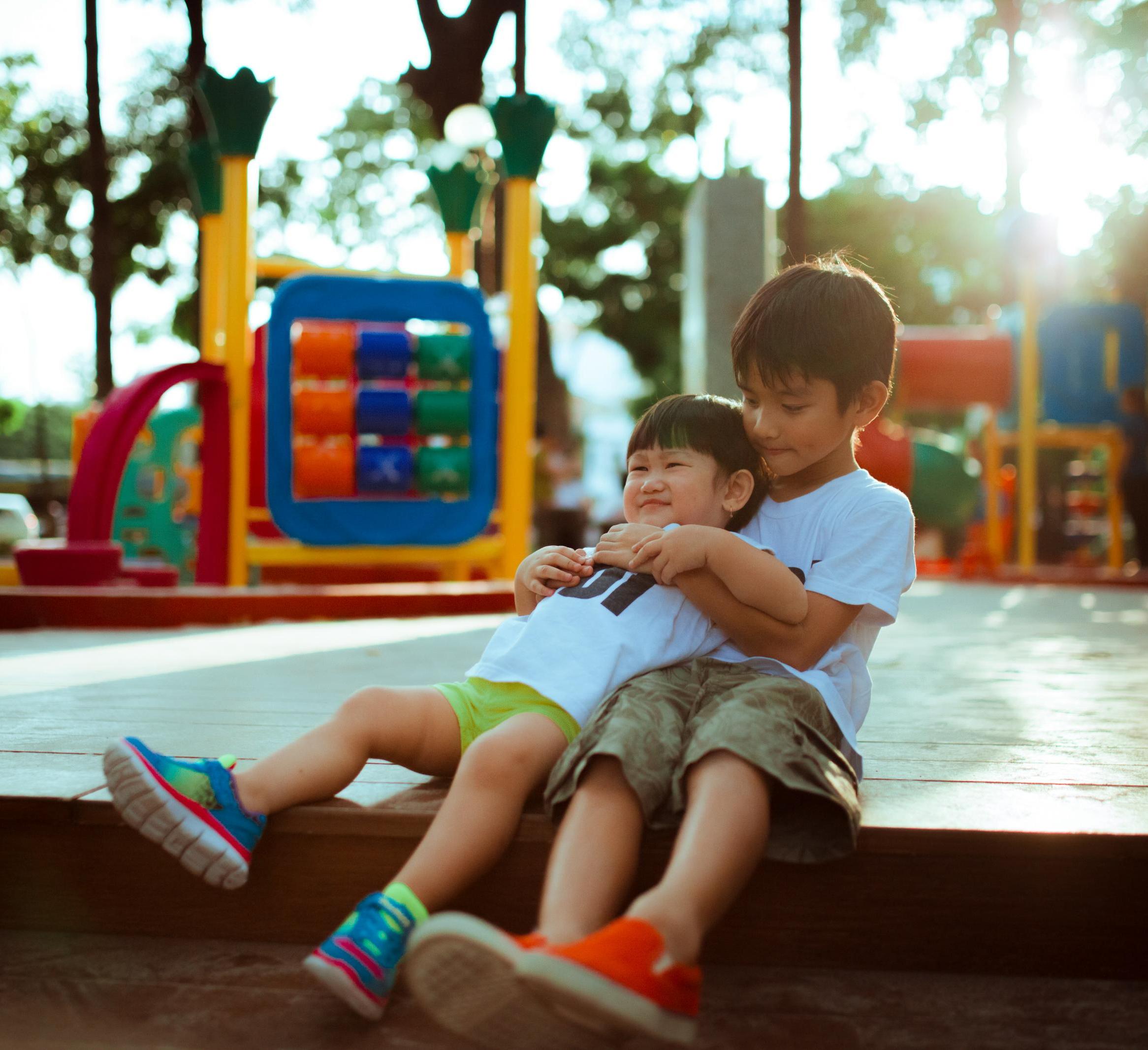 Two Asian children hug