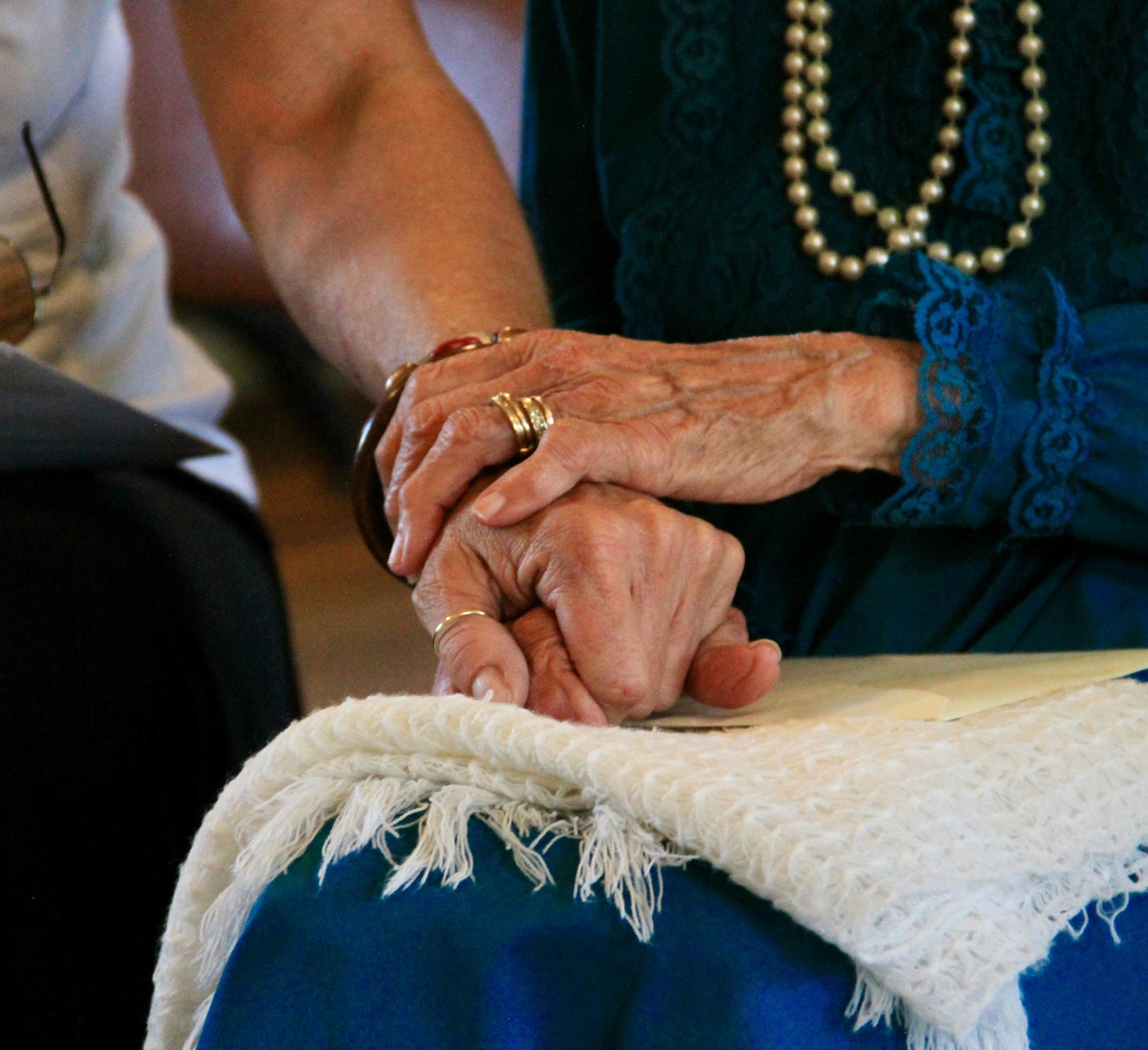 Close up of two people holding hands both older