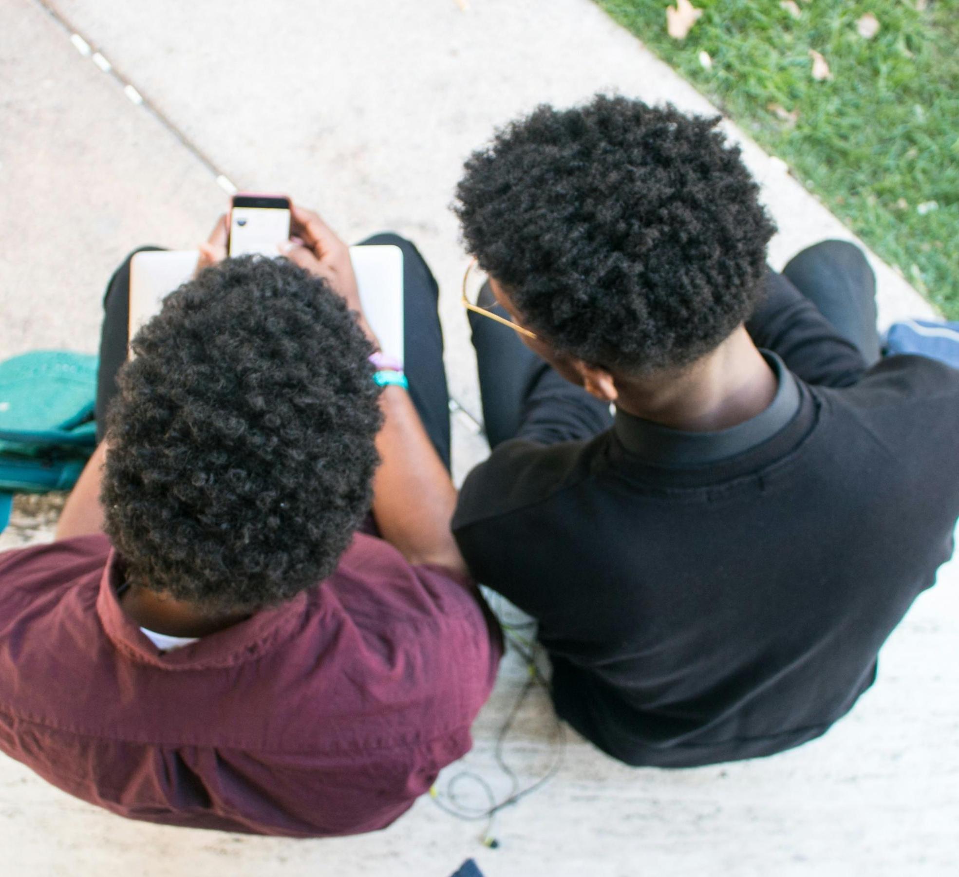 Two teens look at a cell phone together