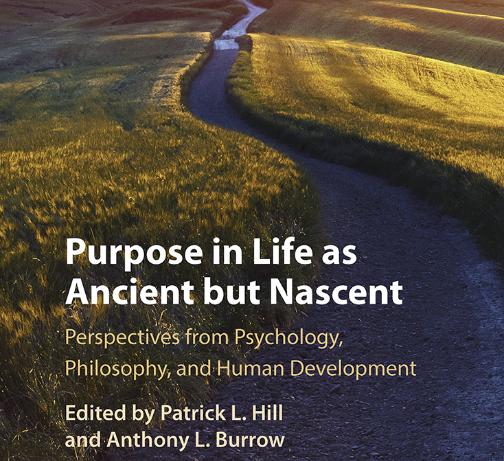 A cover of a book that is a winding road leading to a tree with mountains in the background