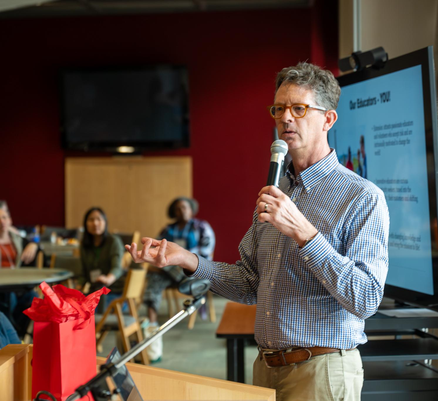 Andy Turner holds a microphone and gives a talk to an audience