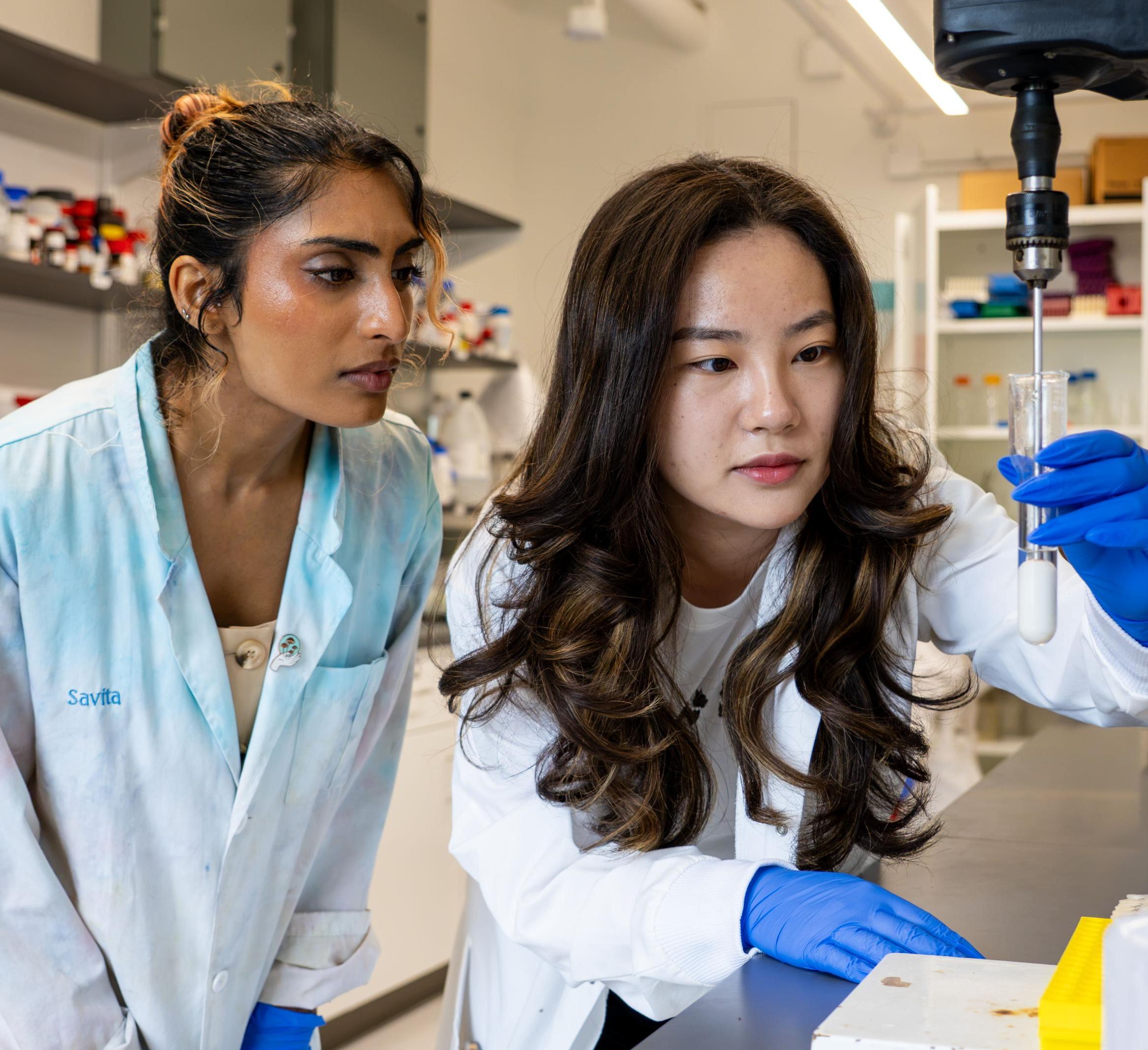 Two students in a lab working with an instrument.