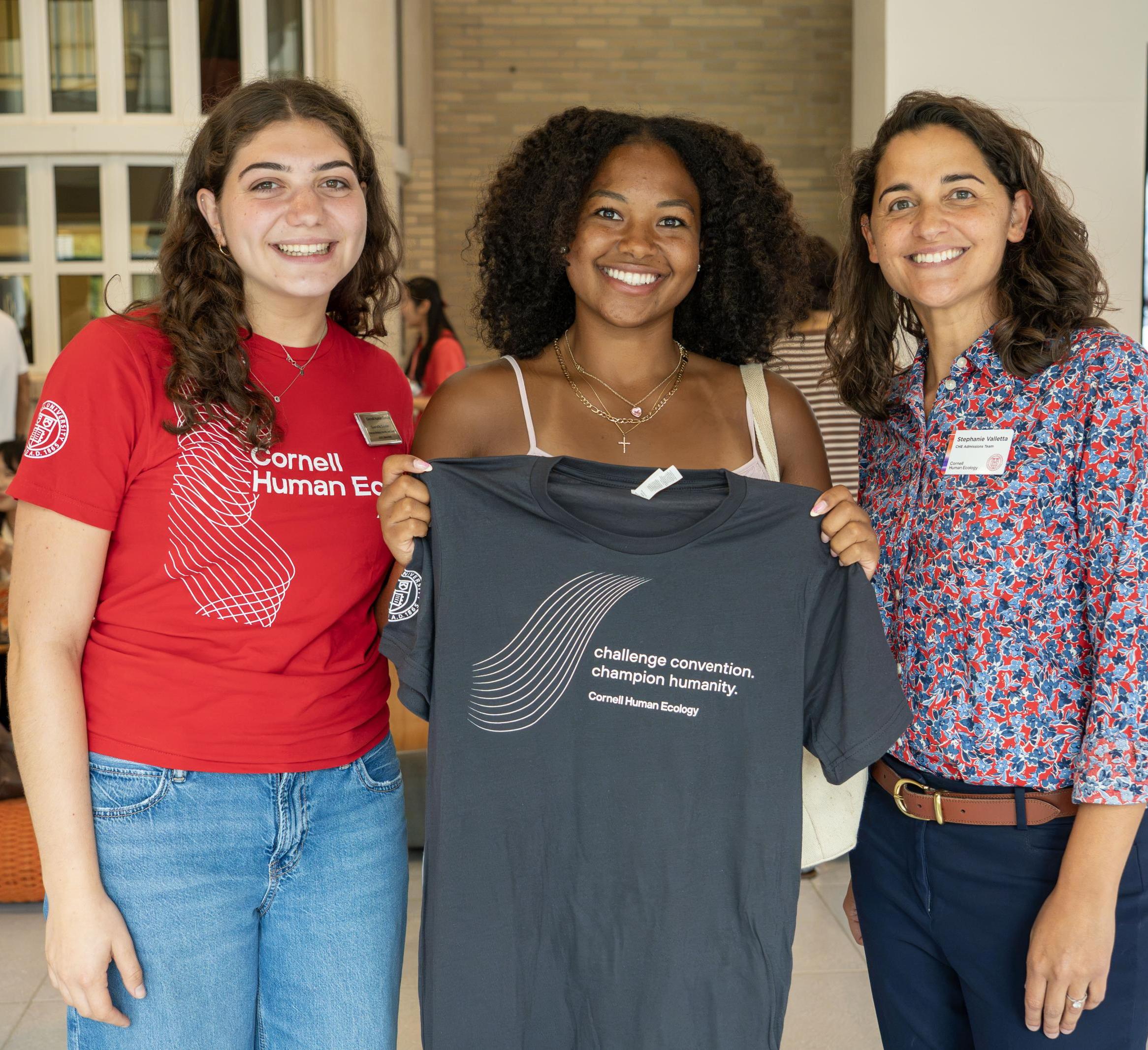 3 women a Orientation holding a CHE tshirt