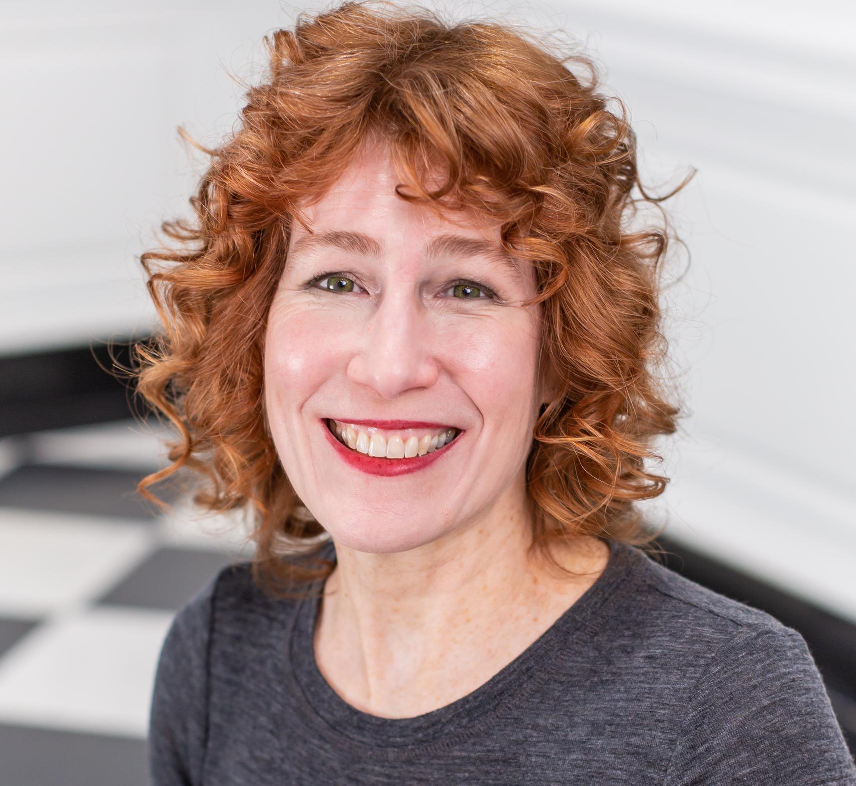 portrait of a woman with red hair and red lipstick in a grey shirt