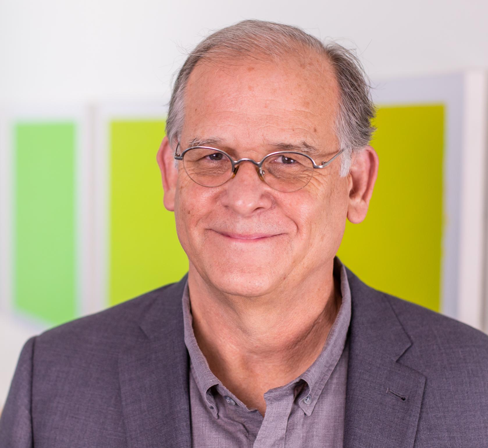 man in a grey suit standing in front of bright green panels