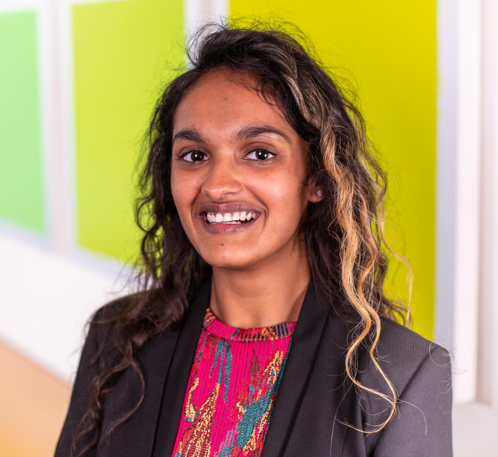 woman with long curly hair standing in front of bright green wall panels