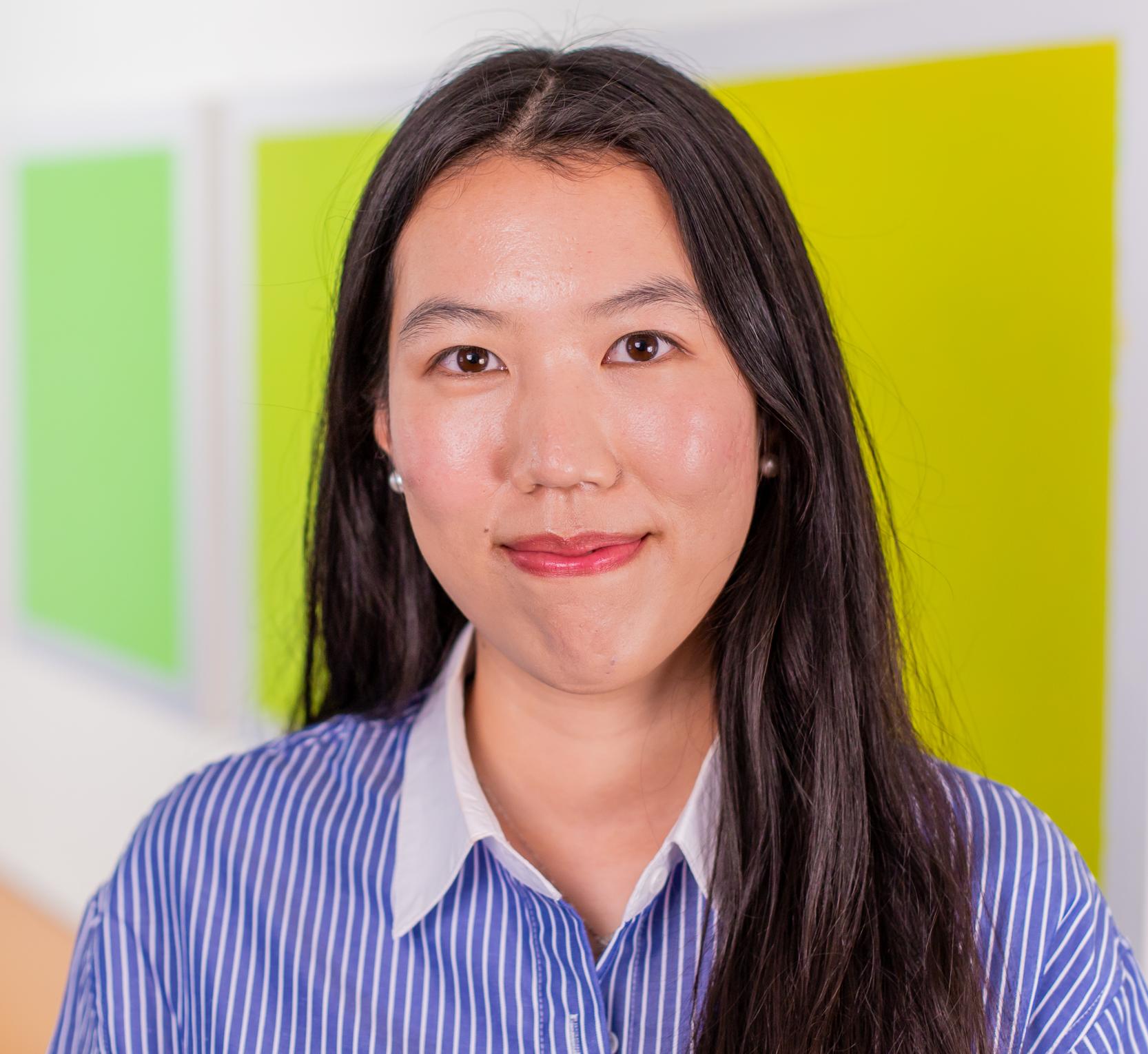 woman in a blue striped button down shirt standing in front of bright green wall panels