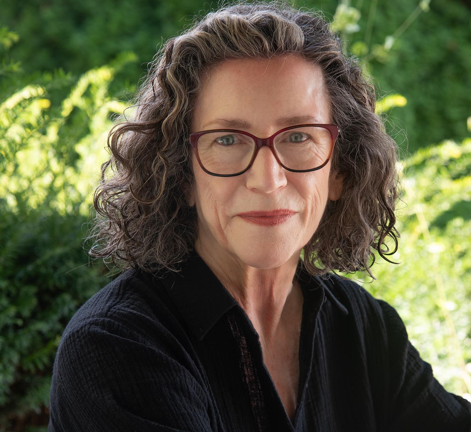 portrait of a woman with curly brown hair and glasses
