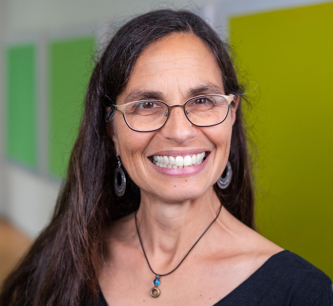 woman wearing glasses standing in front of bright green wall panels