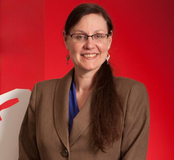 woman wearing a brown blazer standing in front of a red wall