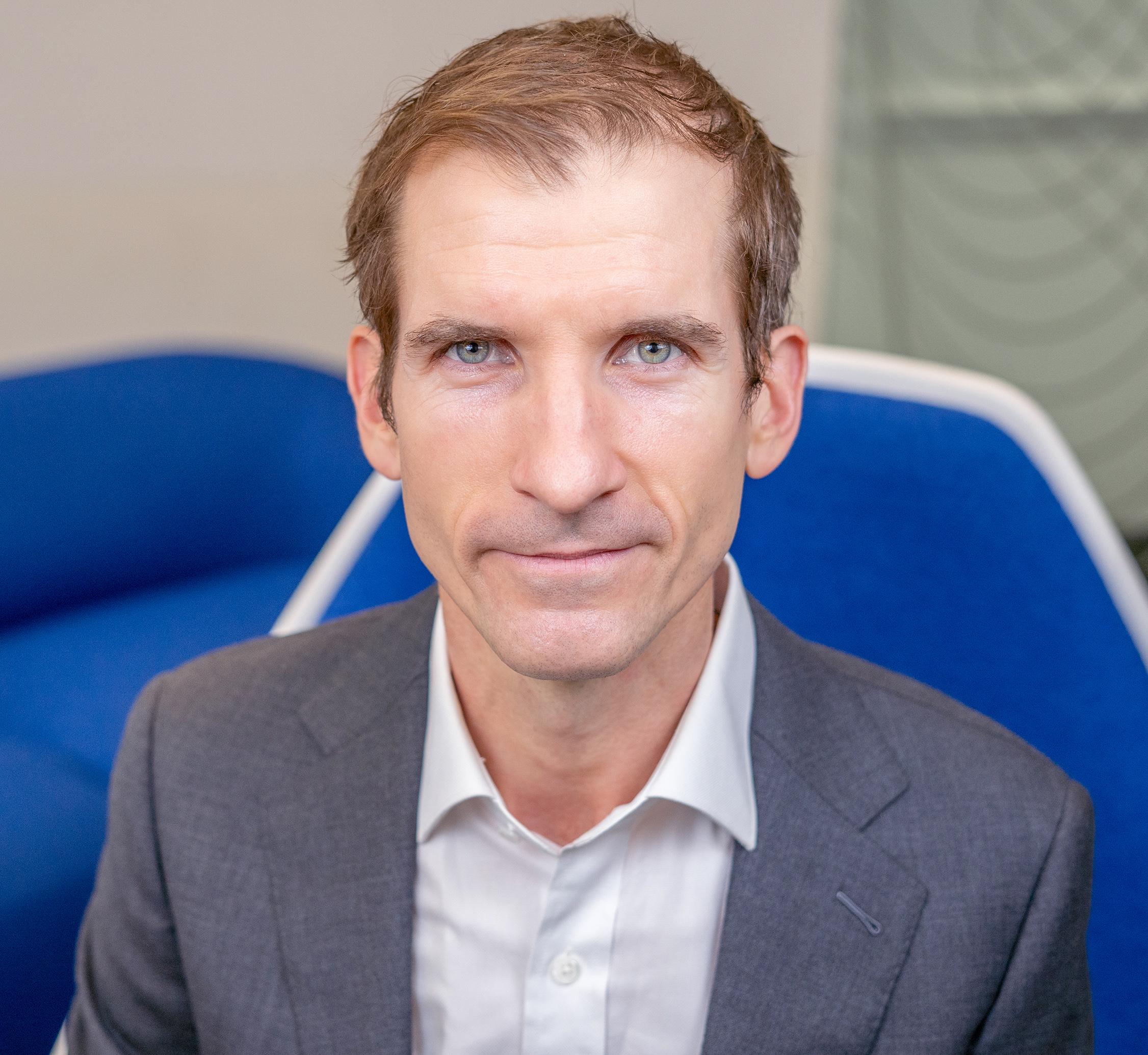 man sitting in a blue chair looking at the camera
