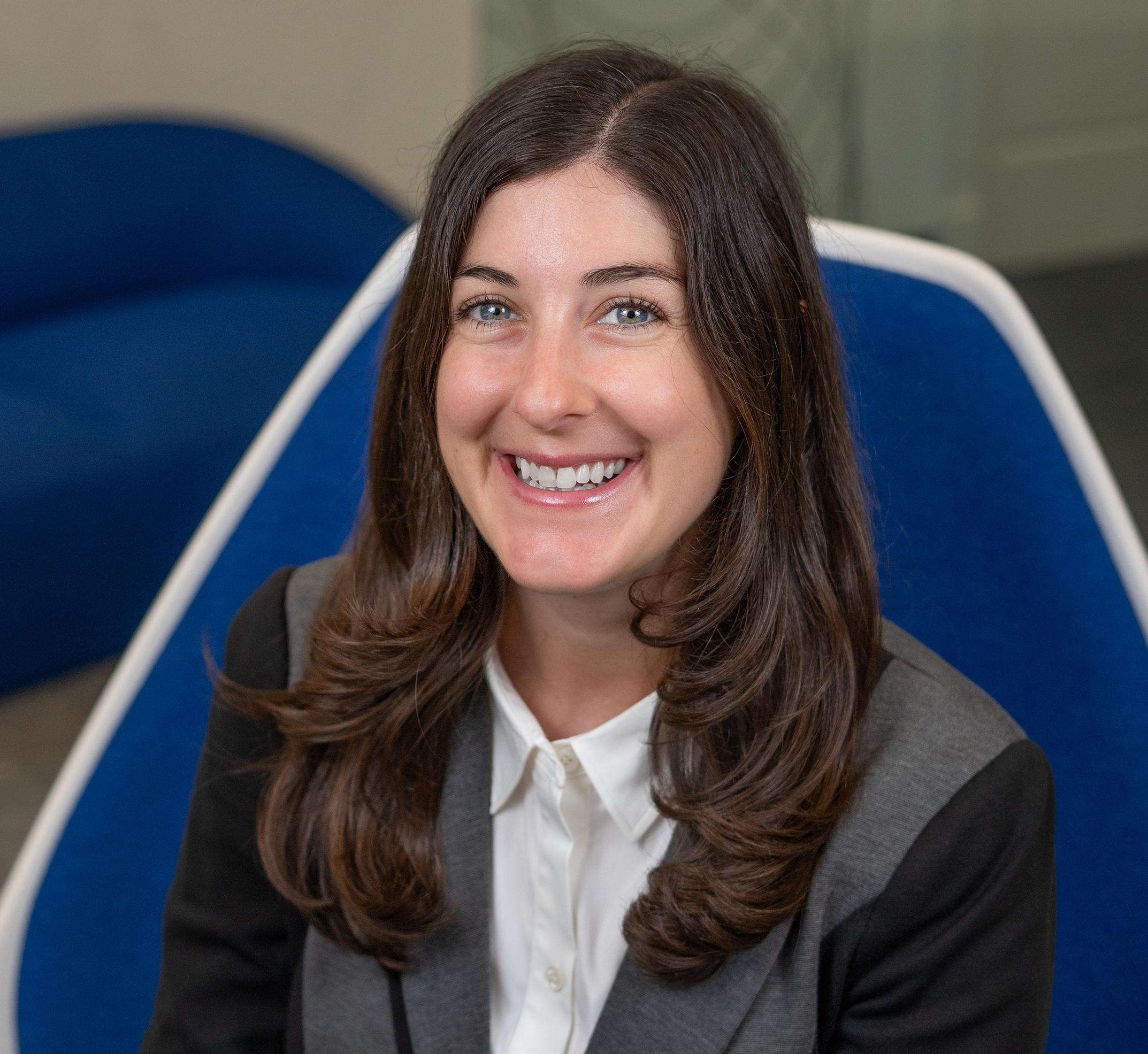 Woman sitting in a blue chair smiling at the camera