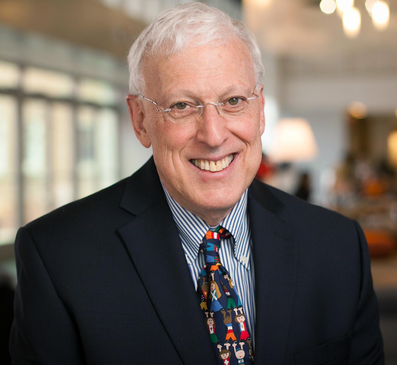 man wearing a colorful tie smiling at the camera