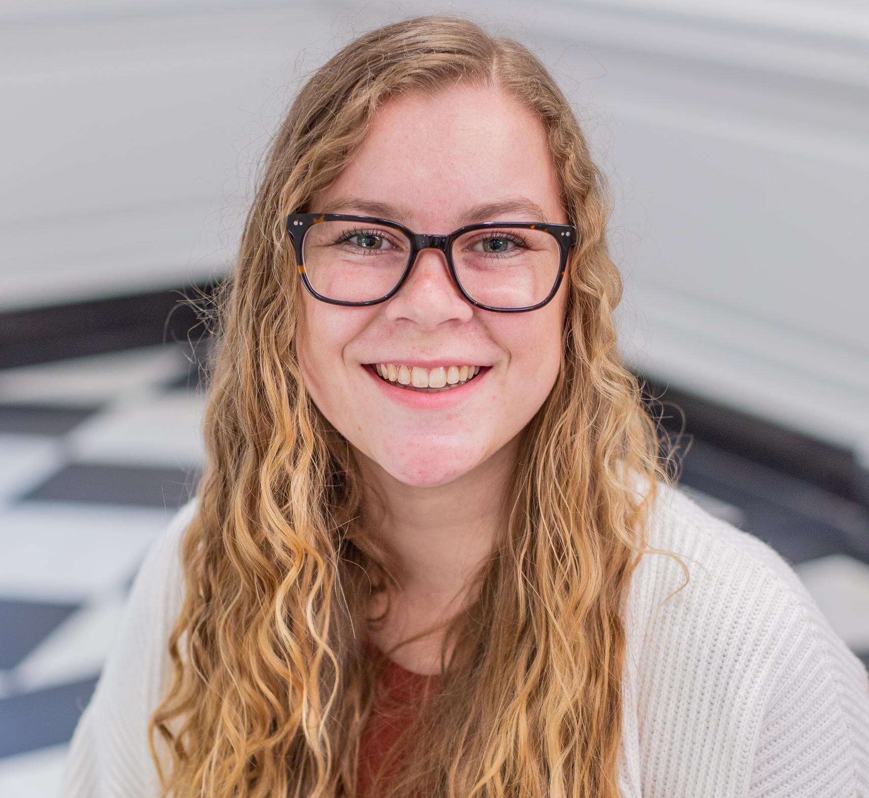 woman with long curly blonde hair and glasses