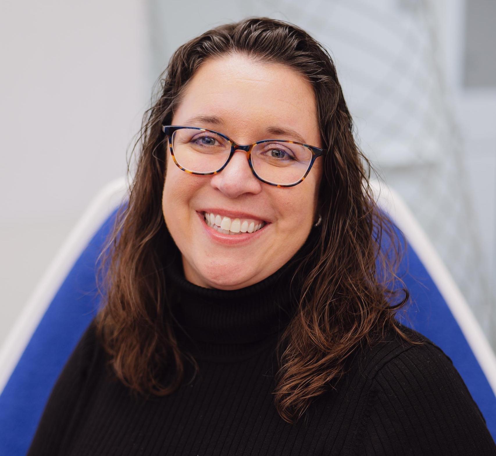 headshot of woman with brown hair and glasses
