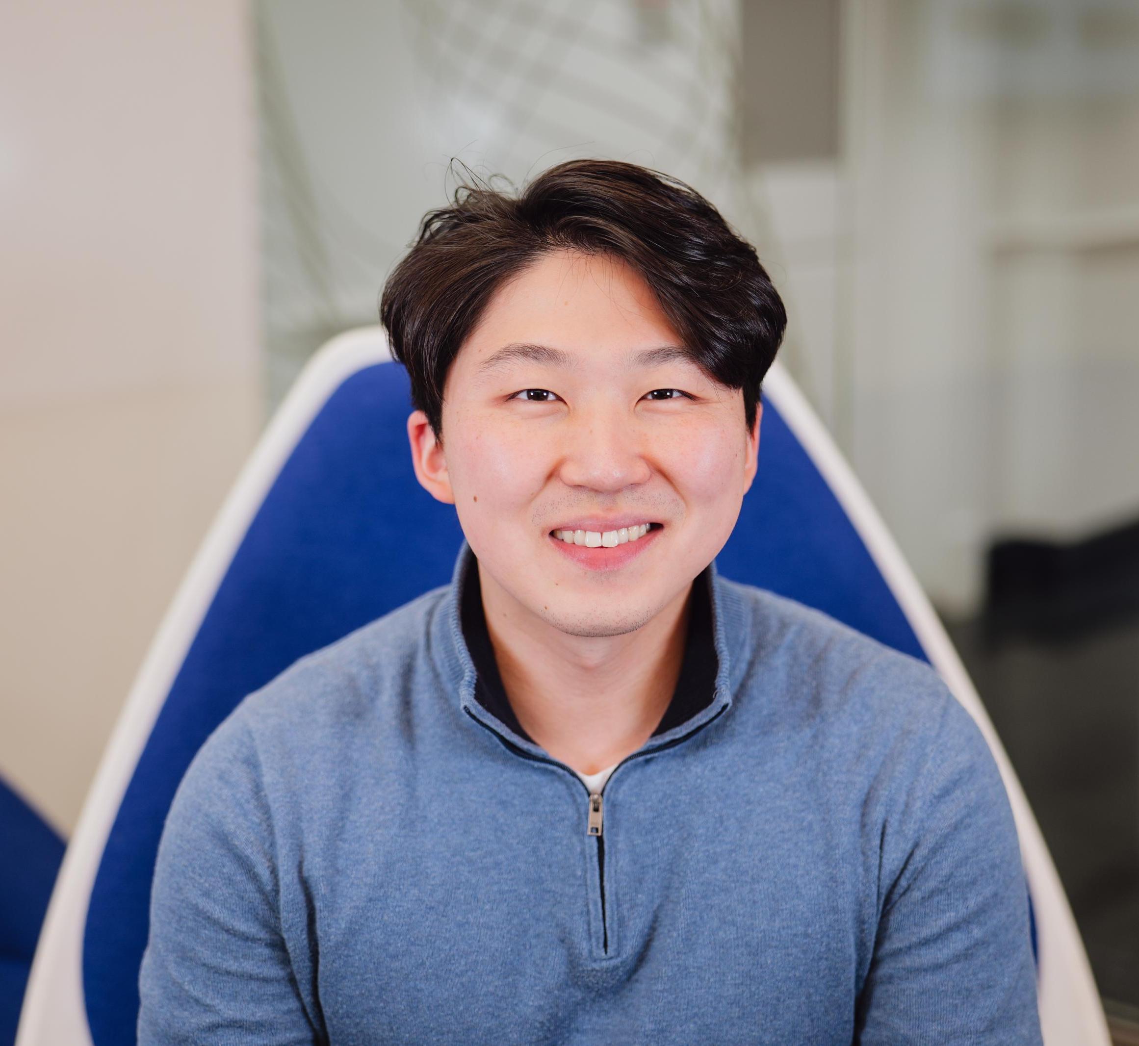 Portrait of Derek Lee sitting in a blue chair