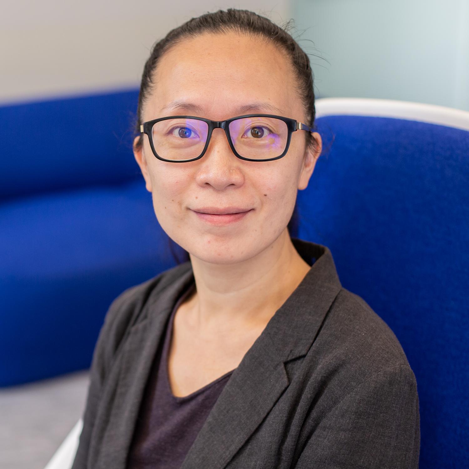 woman wearing glasses sitting in a bright blue chair