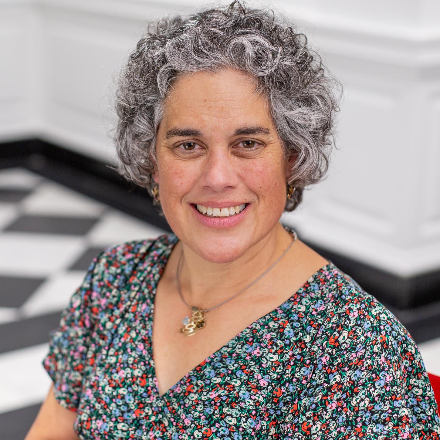 woman with short curly hair and a floral top 