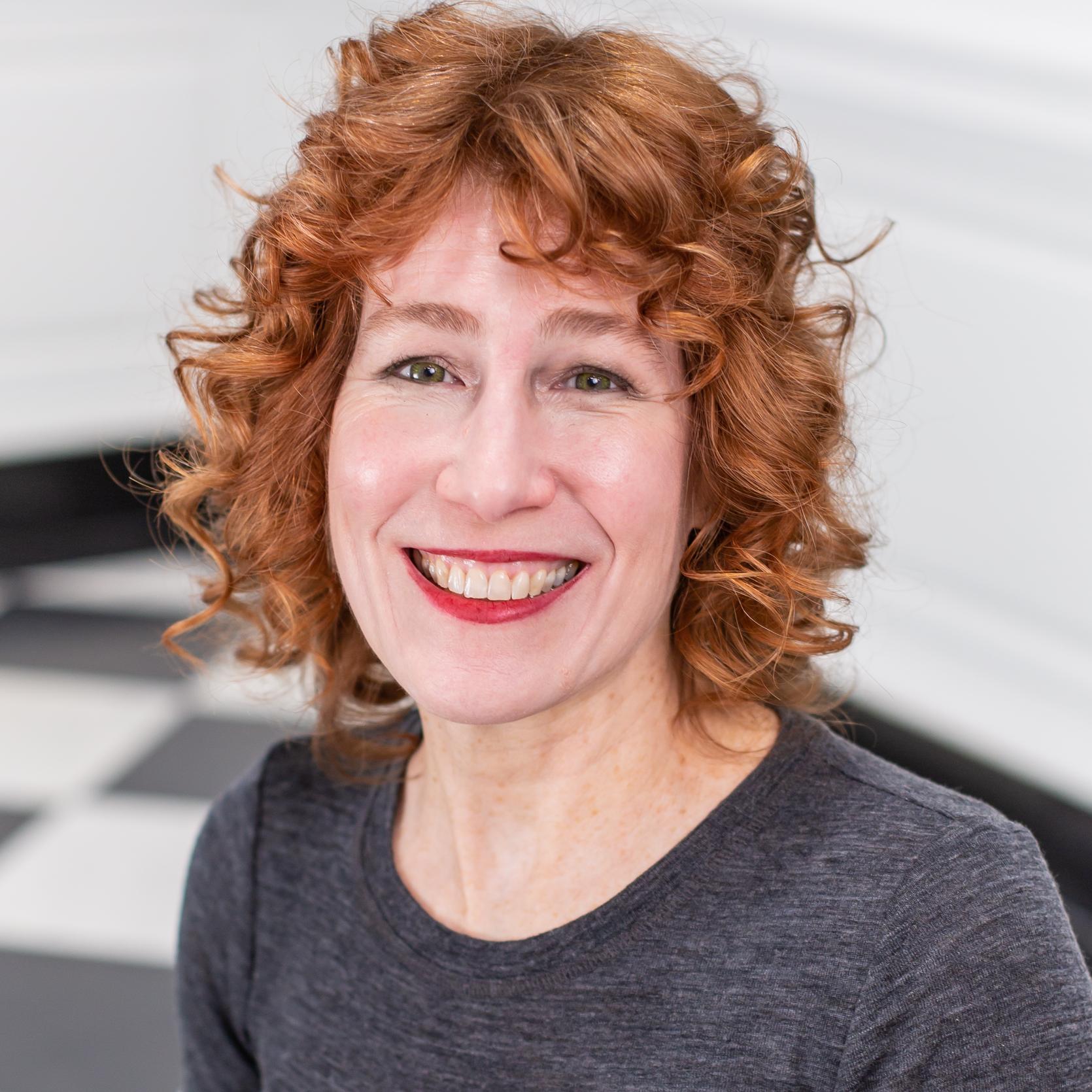 portrait of a woman with red hair and red lipstick in a grey shirt