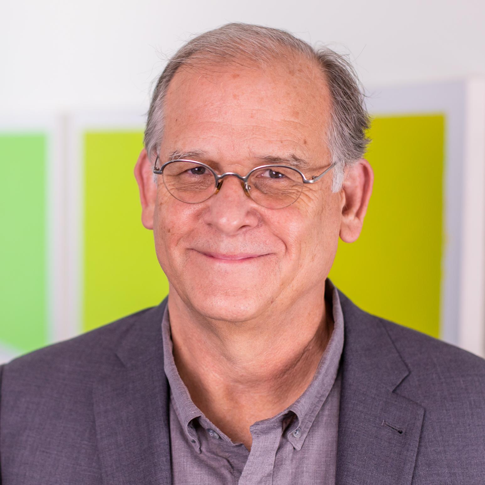 man in a grey suit standing in front of bright green panels