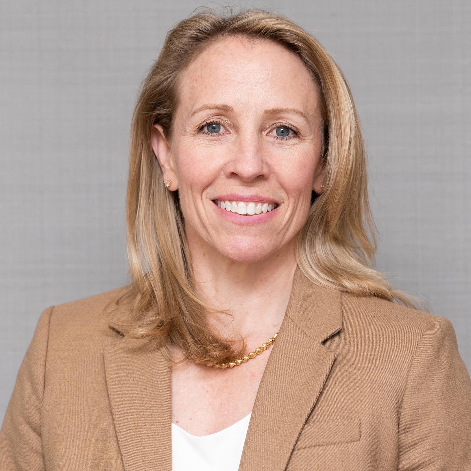 portrait of a smiling blonde woman in a tan blazer