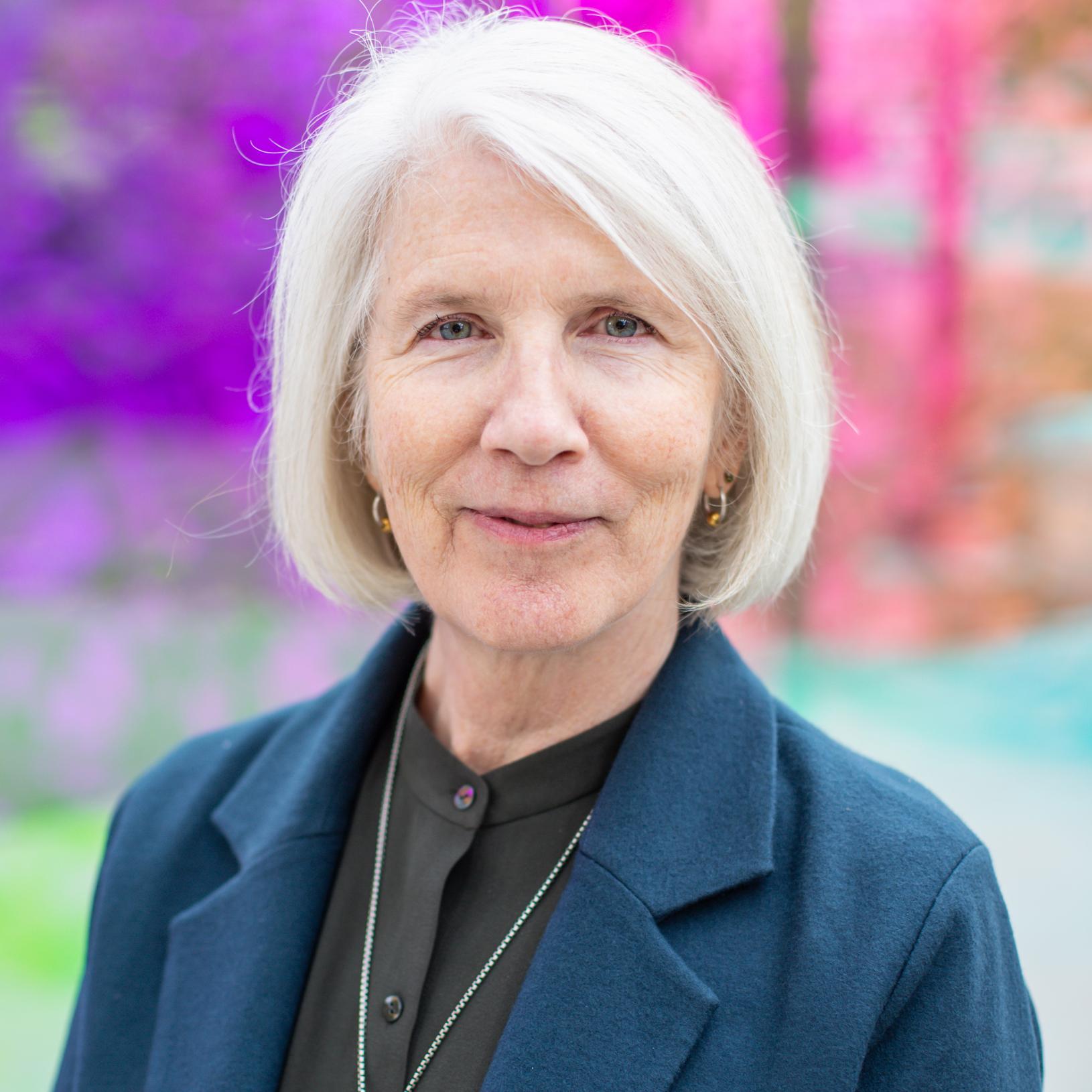 woman wearing a blue blazer and silver pendant necklace