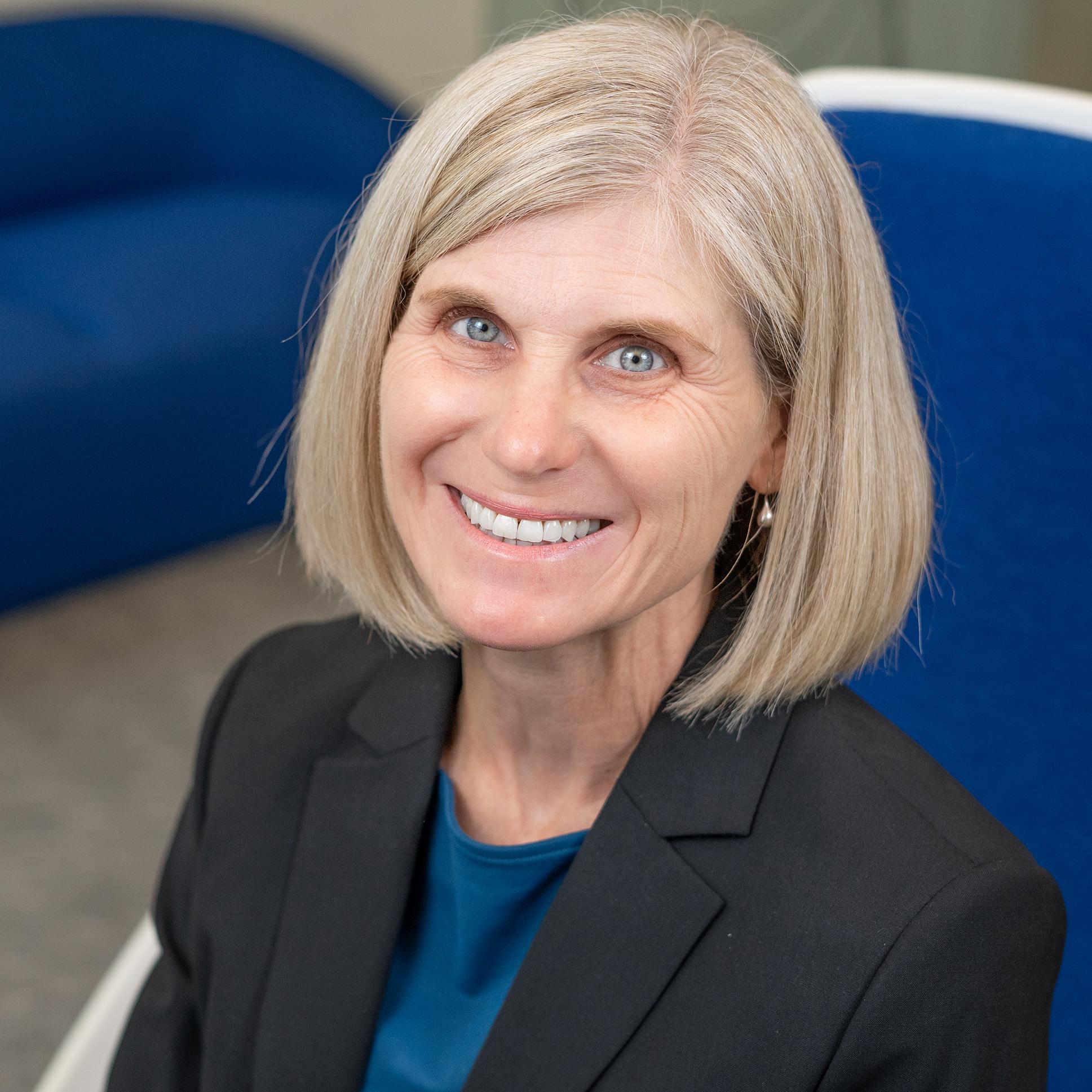 woman sitting in a bright blue chair smiling
