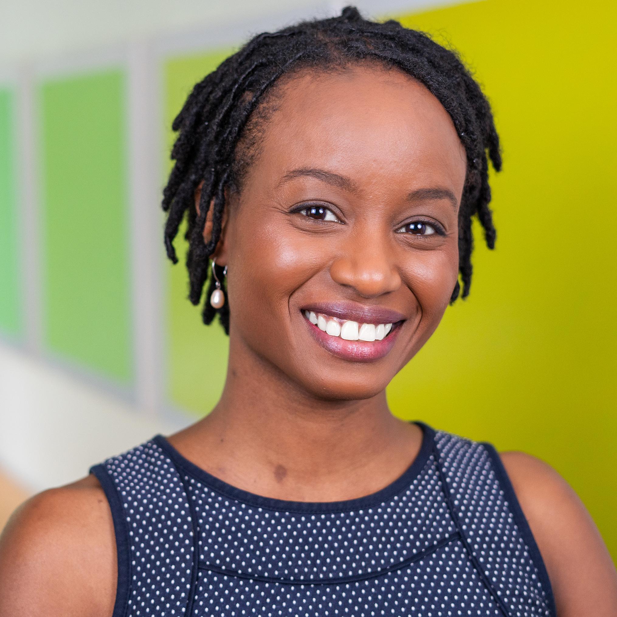 woman smiling at the camera with a background of artwork made up of bright green squares