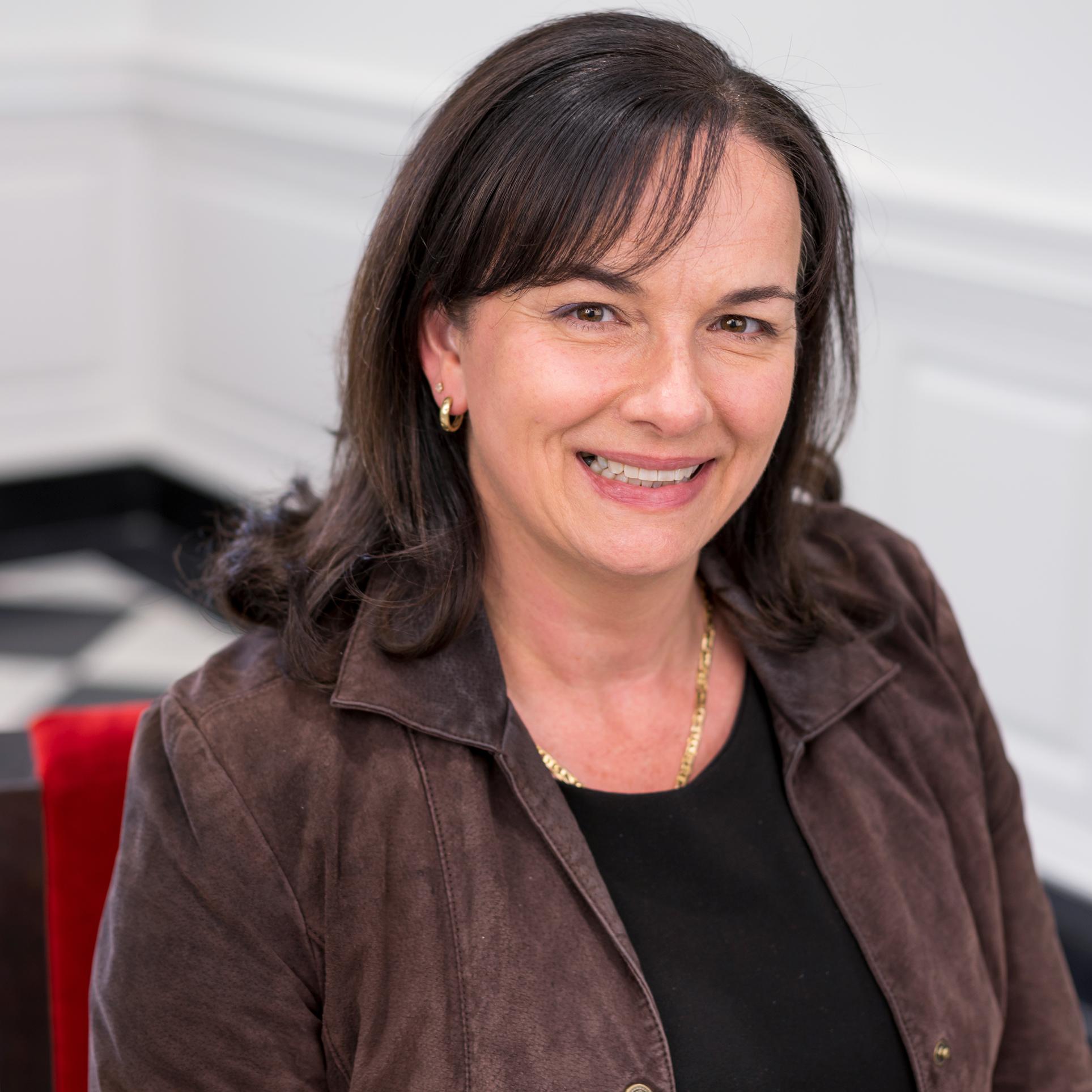 woman in a brown shirt smiling at the camera