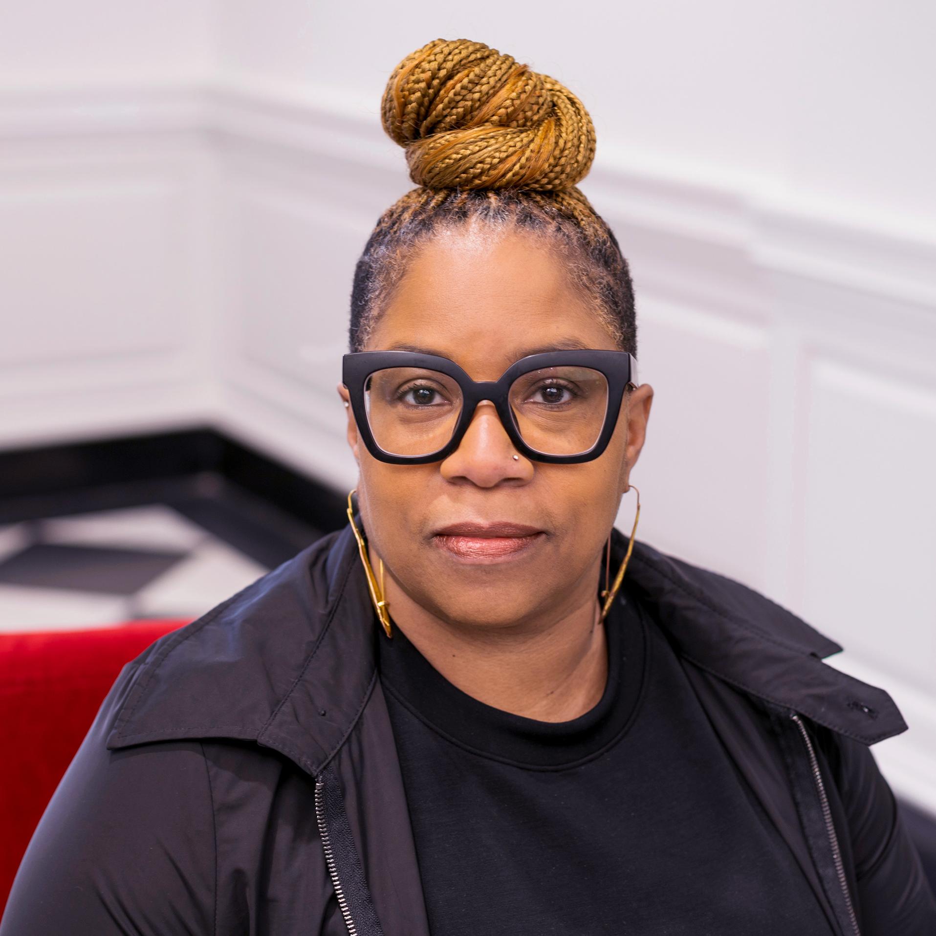 portrait of a woman in black framed glasses looking at the camera