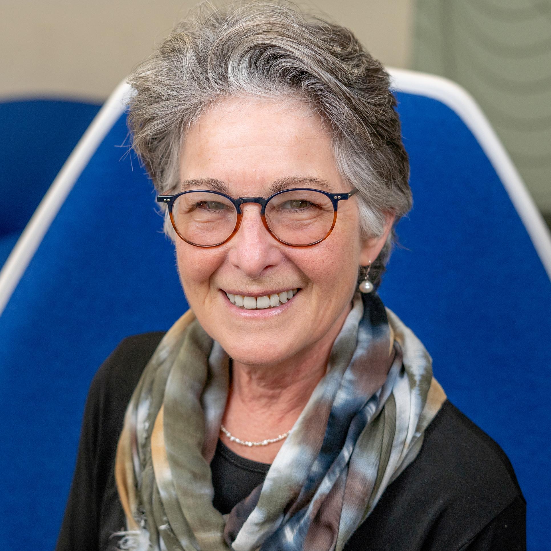 woman wearing glasses sitting in a blue chair