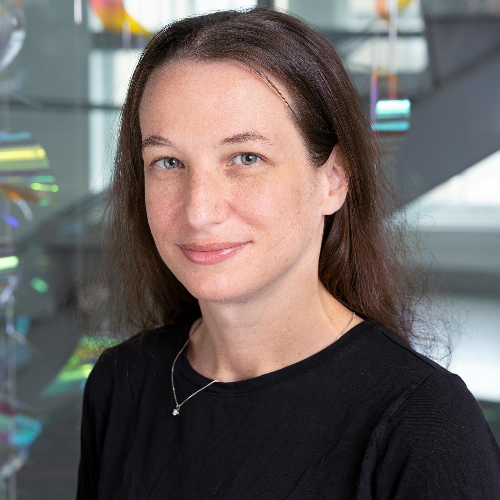 woman in a black shirt with an iridescent mobile hanging behind her 