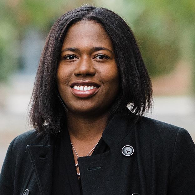 portrait of a woman wearing a dark coat standing in a garden