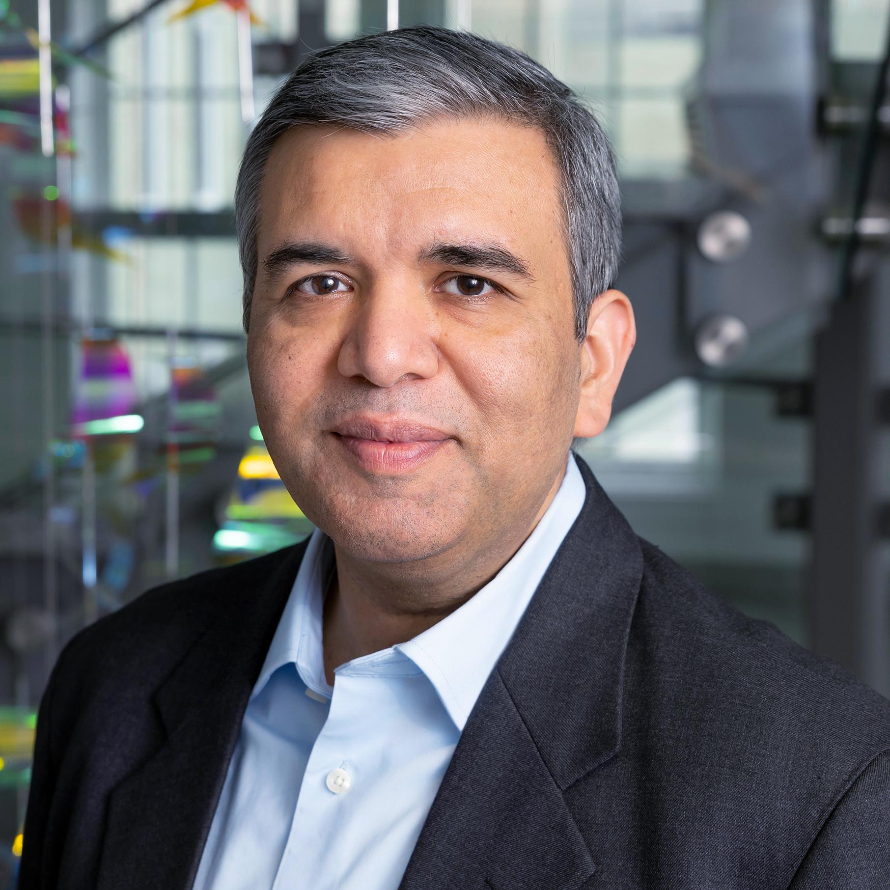 portrait of a man with a colorful hanging sculpture behind him