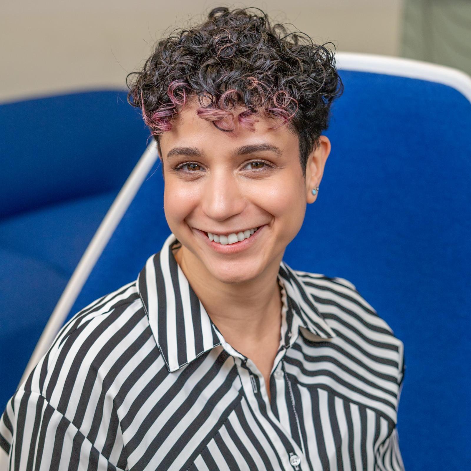 woman in a striped shirt sitting in a bright blue chair