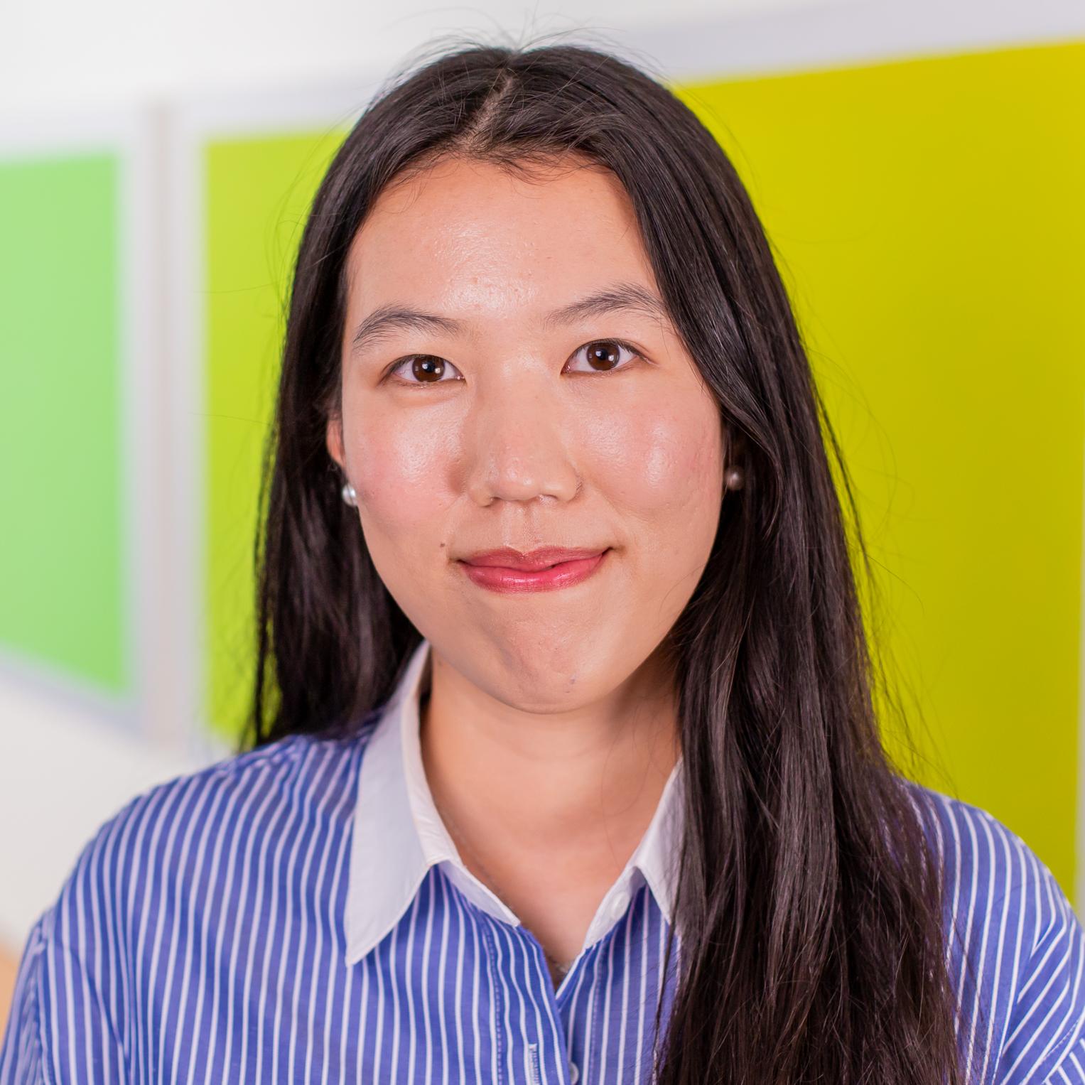 woman in a blue striped button down shirt standing in front of bright green wall panels