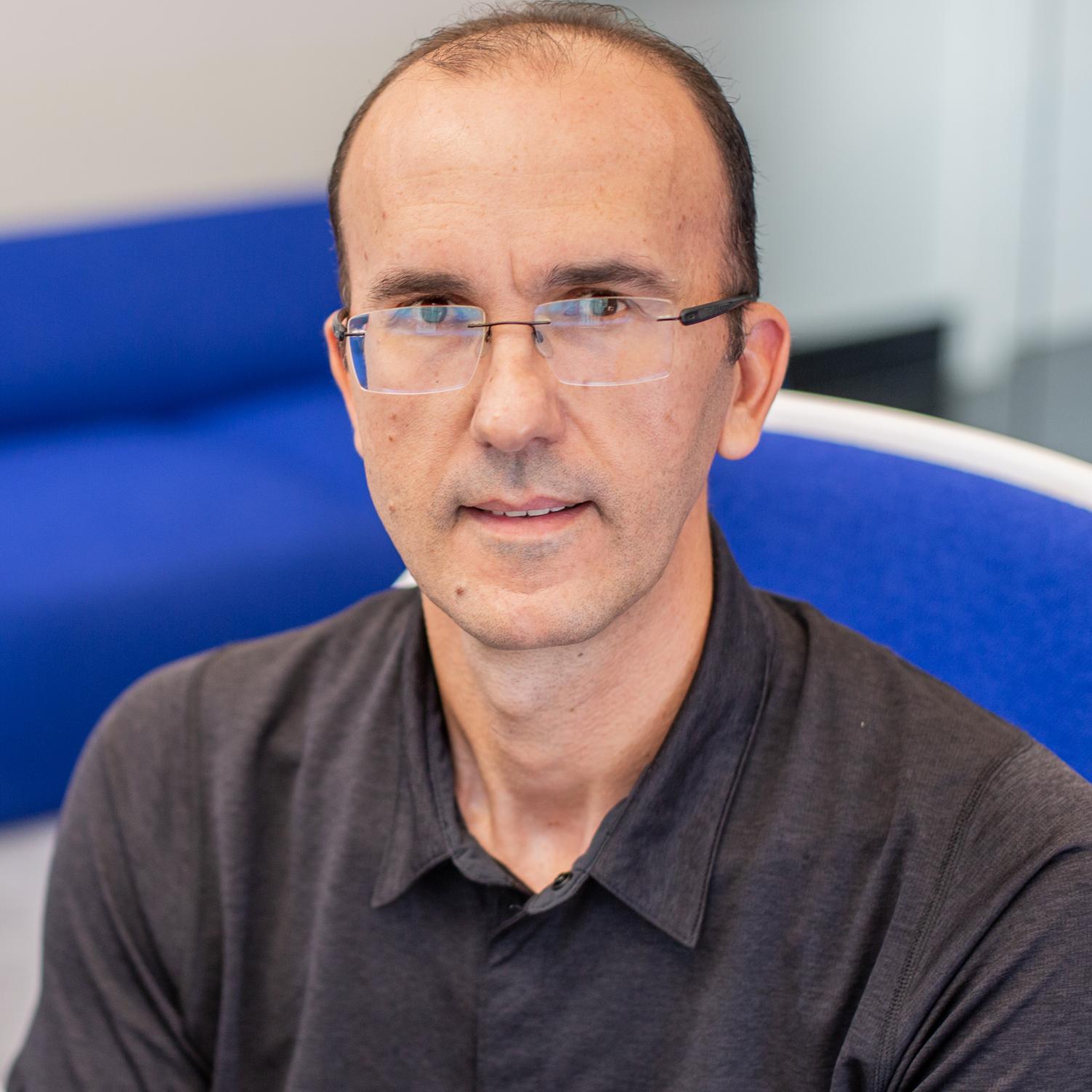 man wearing glasses sitting in a bright blue chair