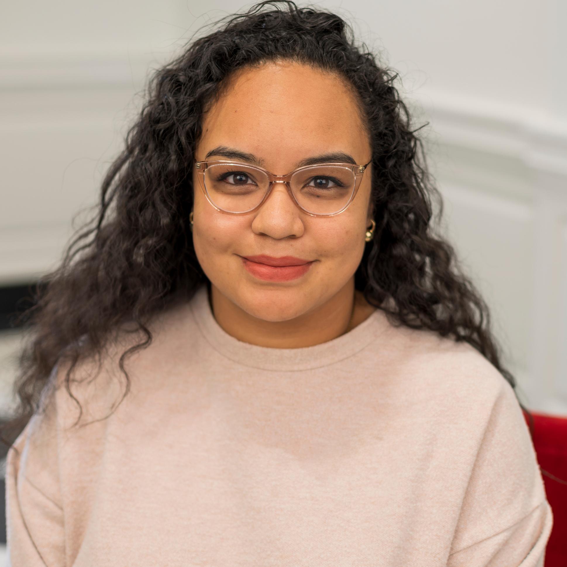 portrait of a woman wearing glasses sitting in a red chair