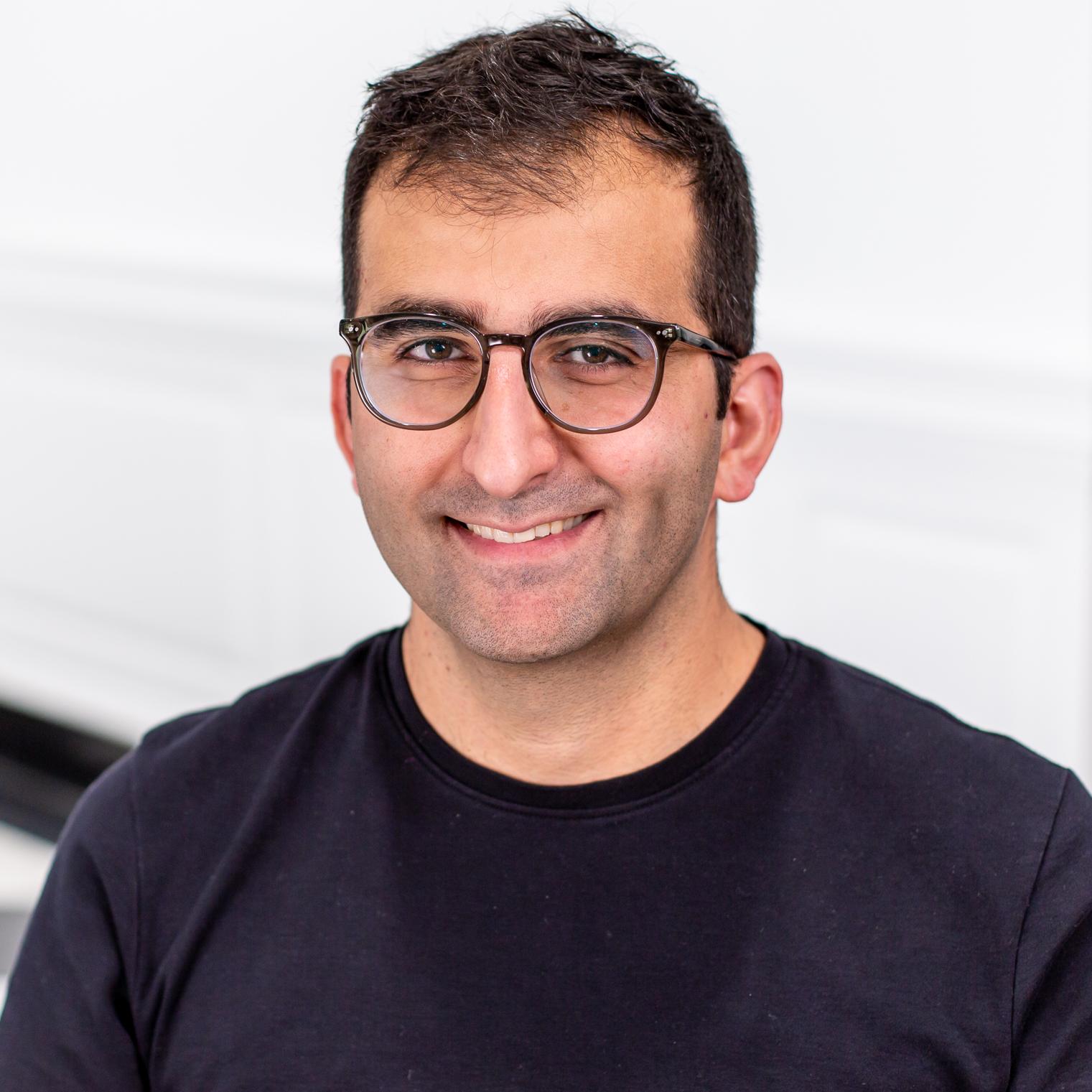 portrait of a man wearing glasses and a blue shirt