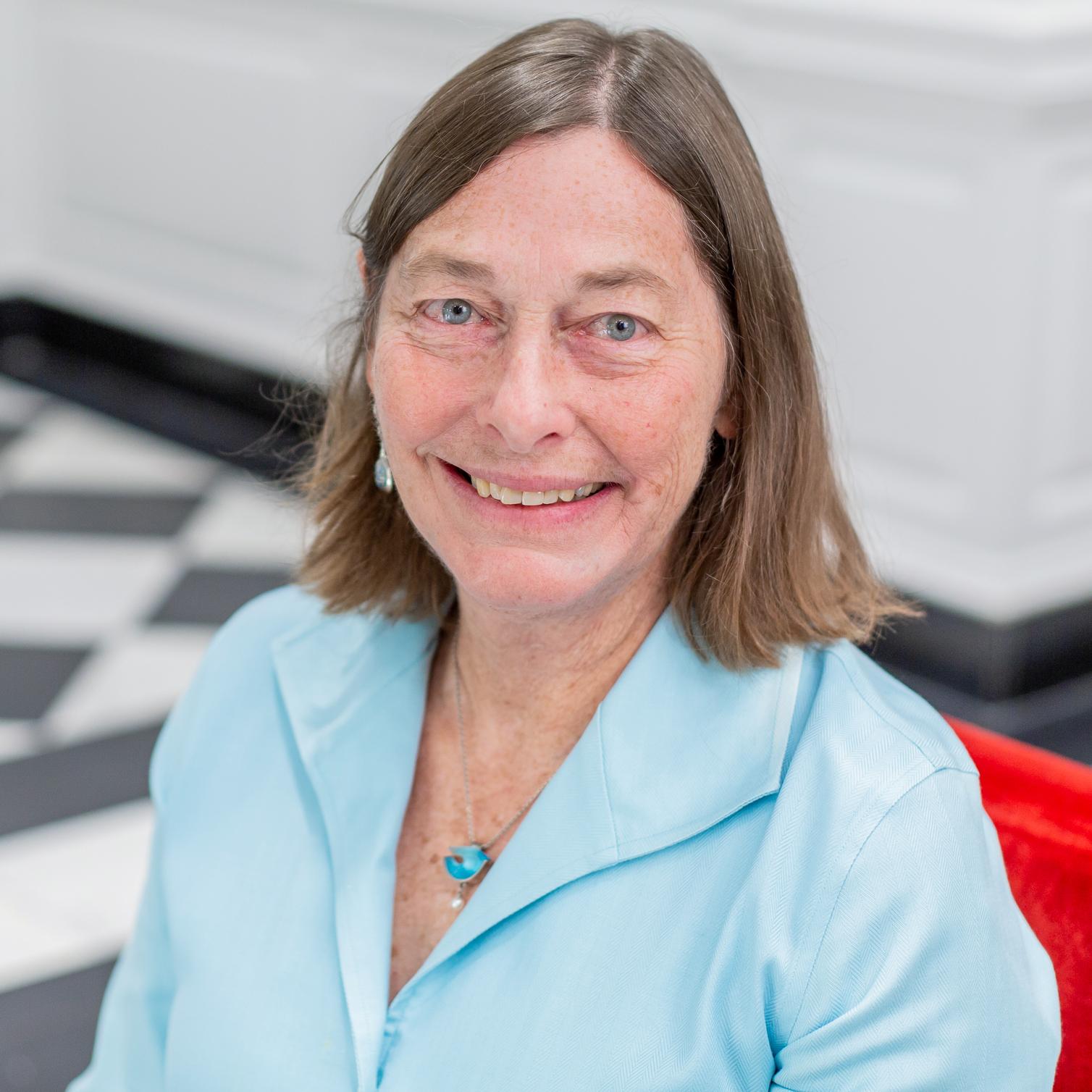 portrait of a woman in a light blue shirt sitting in a red chair