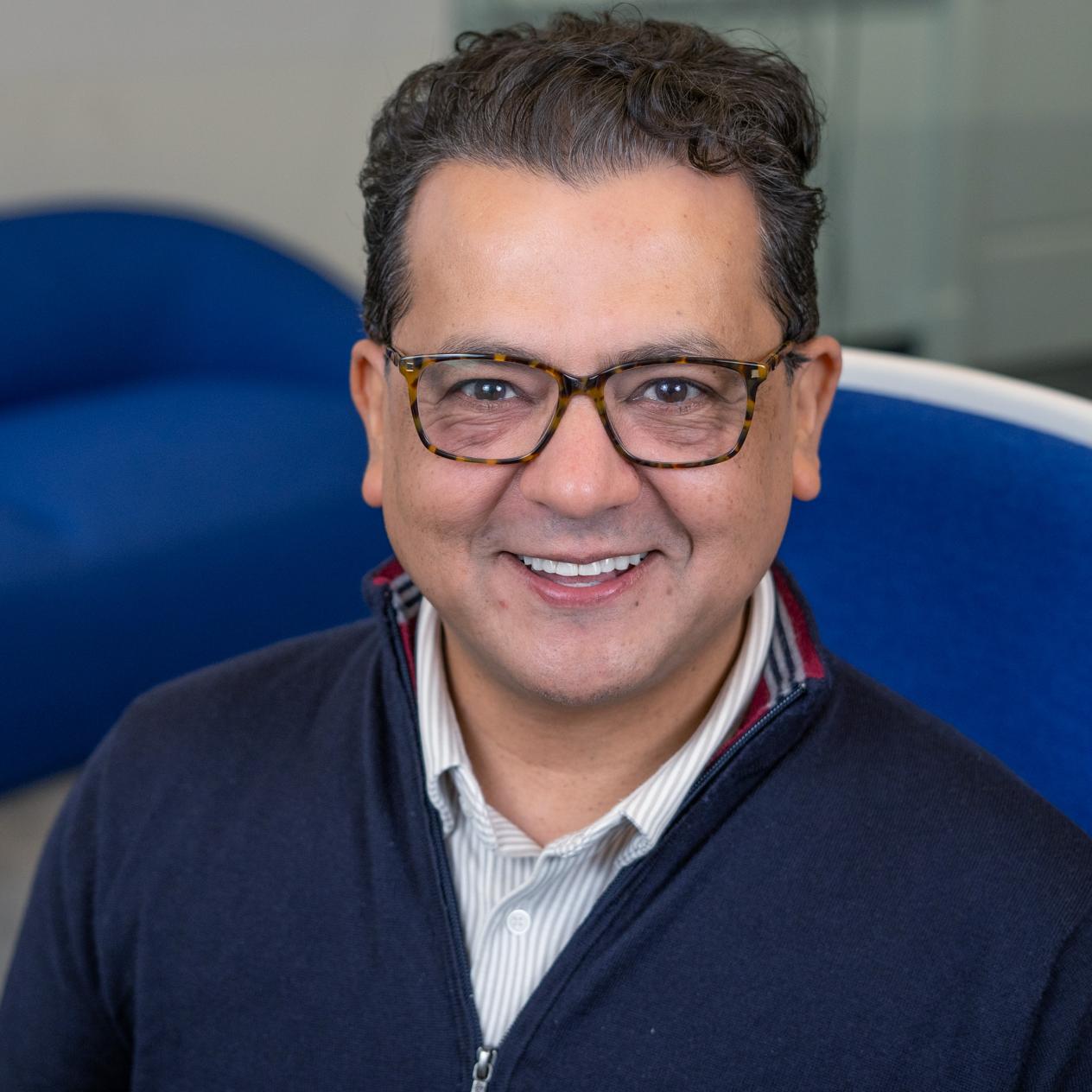 smiling man sitting in a blue chair