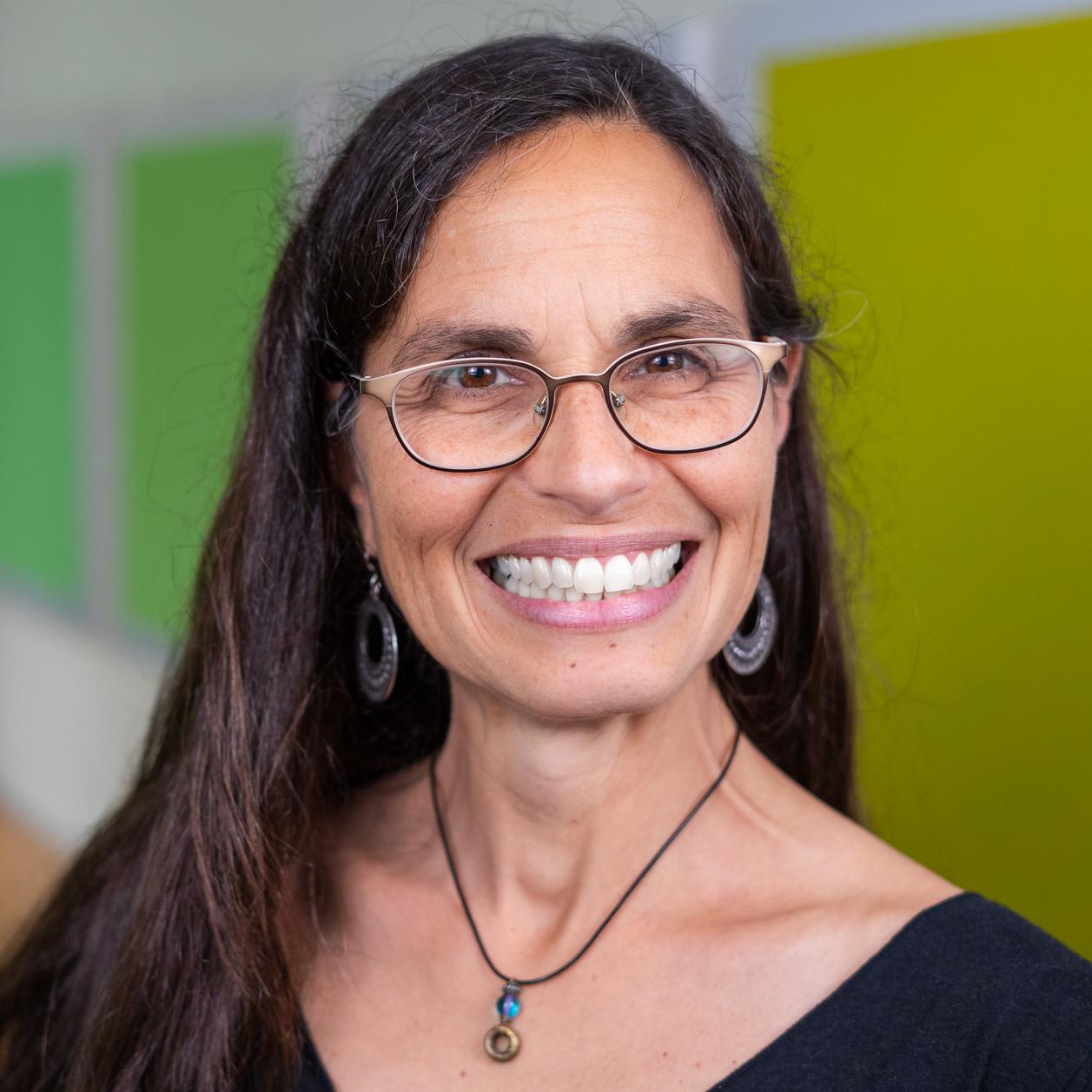 woman wearing glasses standing in front of bright green wall panels