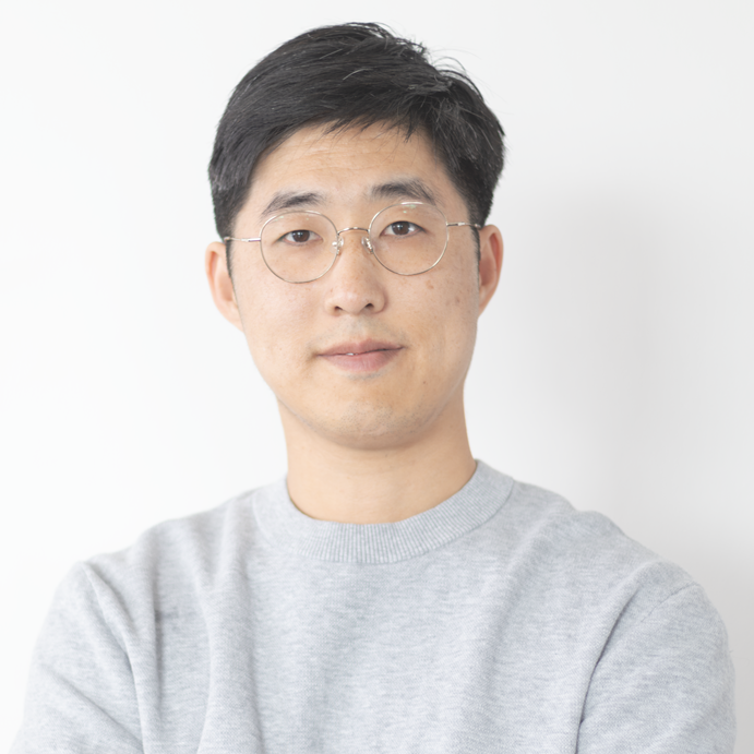 portrait of a man with round glasses wearing a grey t-shirt