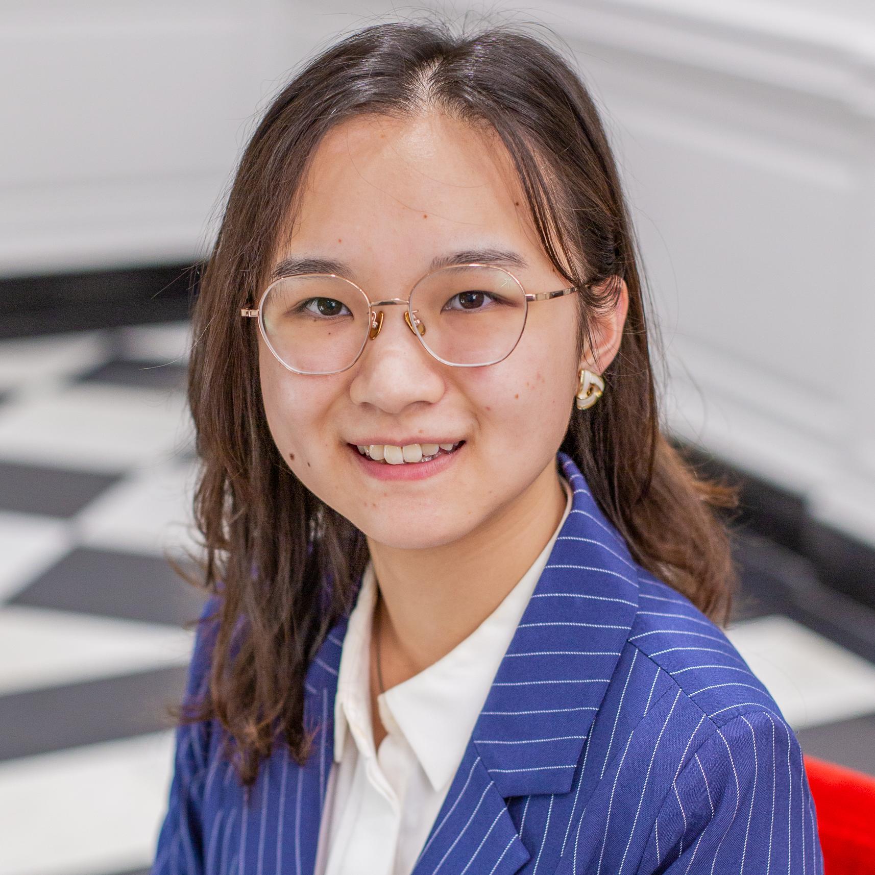 person with long brown hair and glasses wearing a blue blazer
