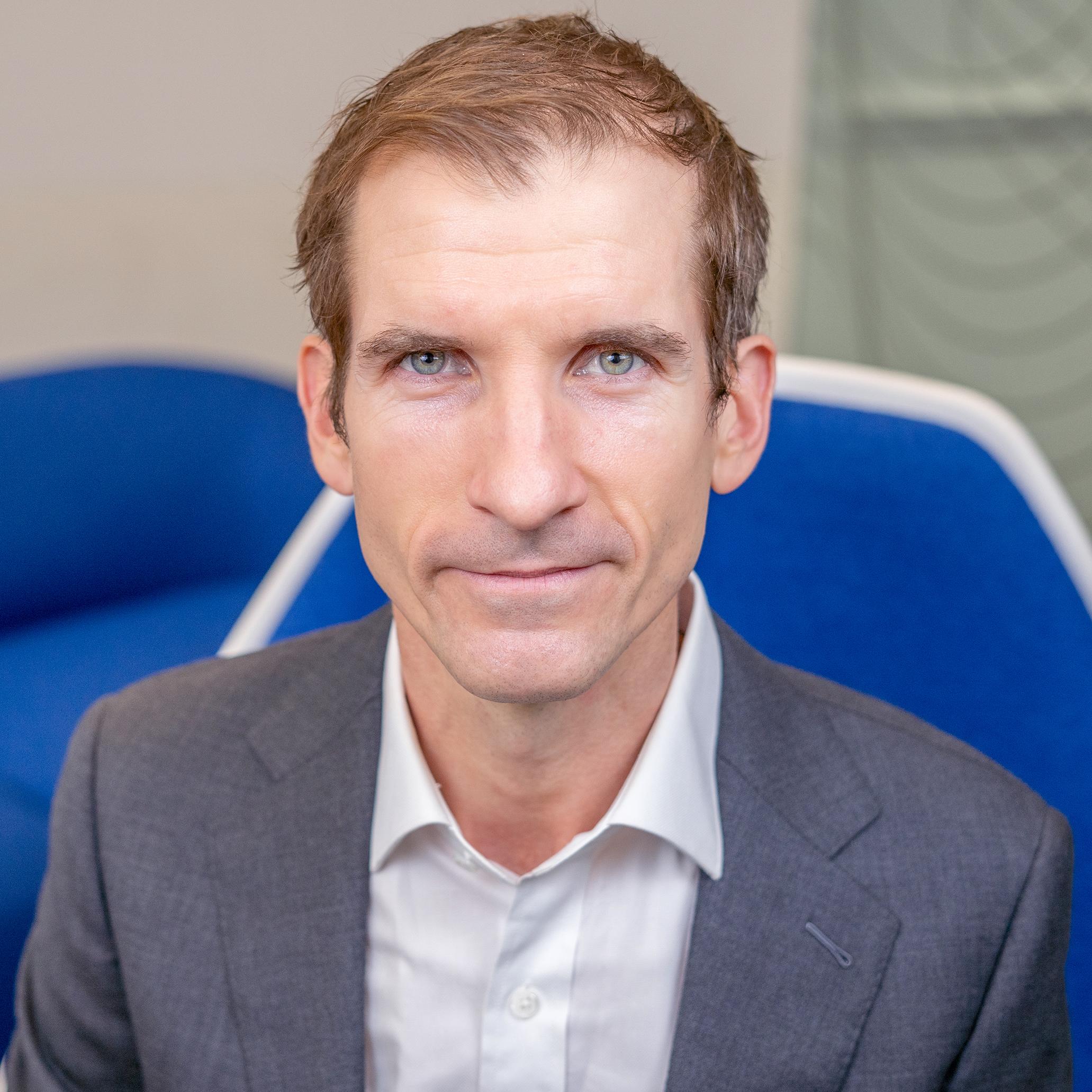 man sitting in a blue chair looking at the camera