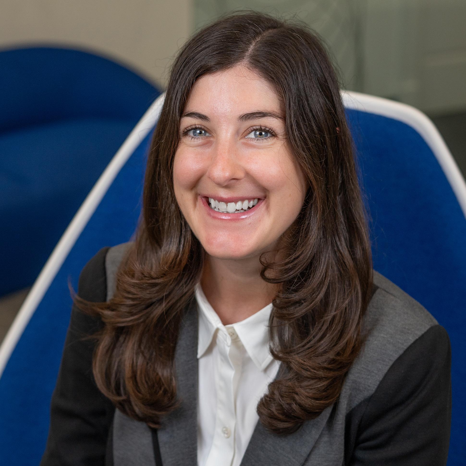 Woman sitting in a blue chair smiling at the camera