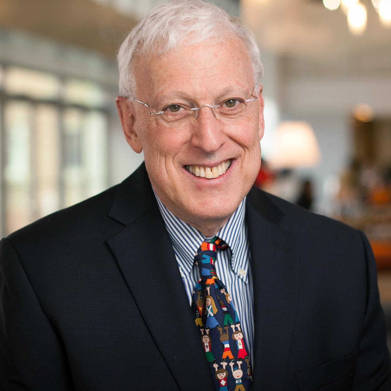 man wearing a colorful tie smiling at the camera