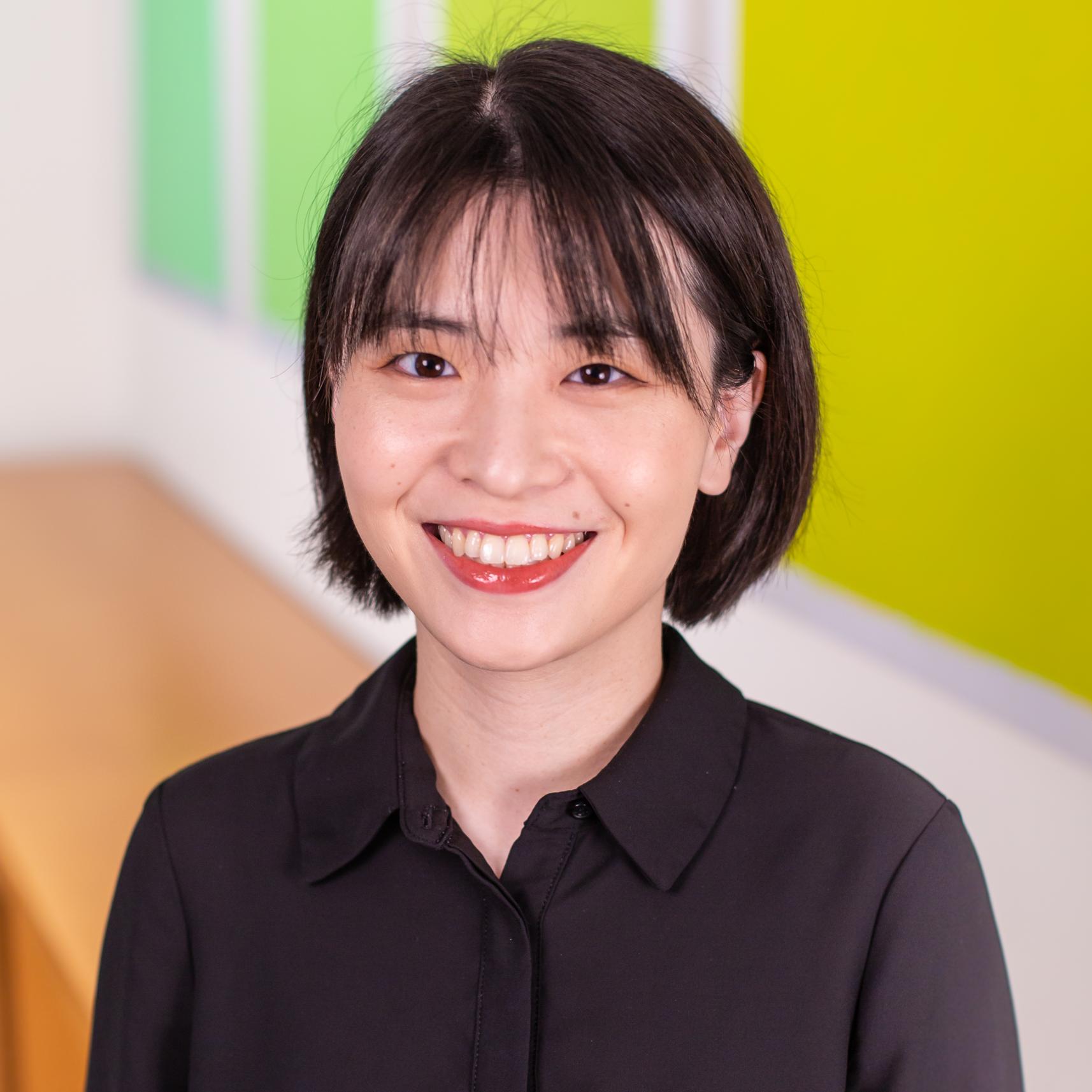 portrait of a woman standing in front of bright green panels