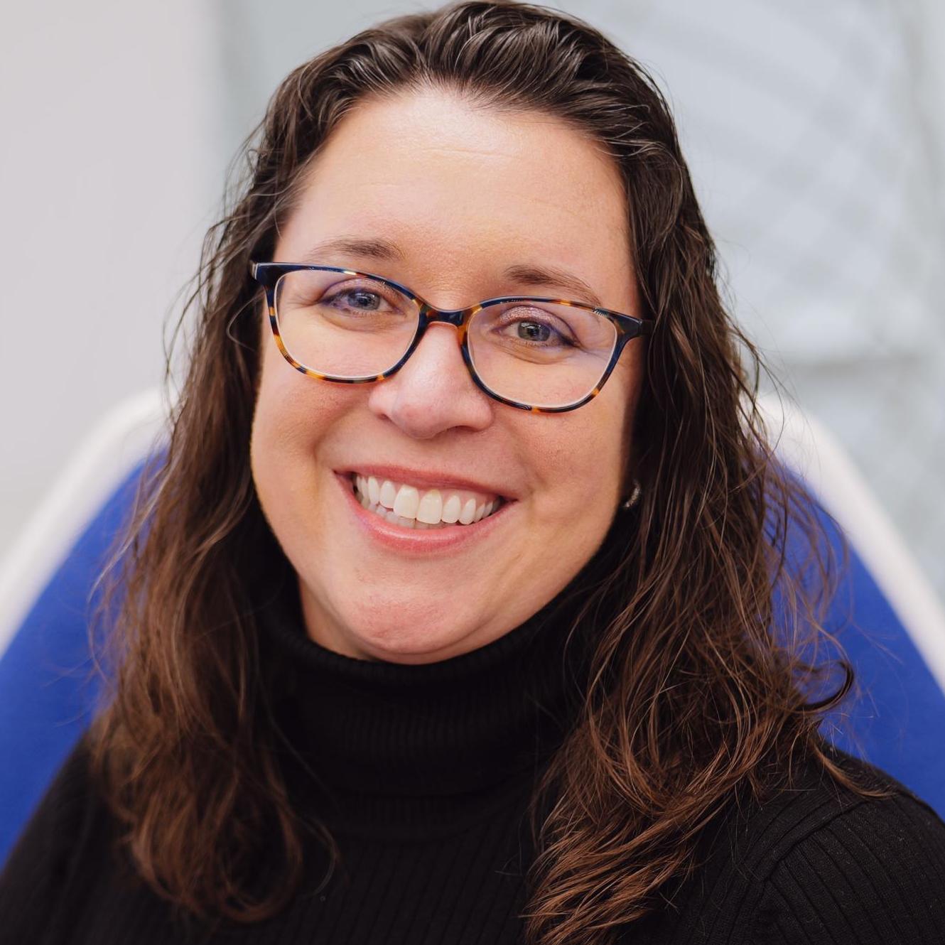 headshot of woman with brown hair and glasses