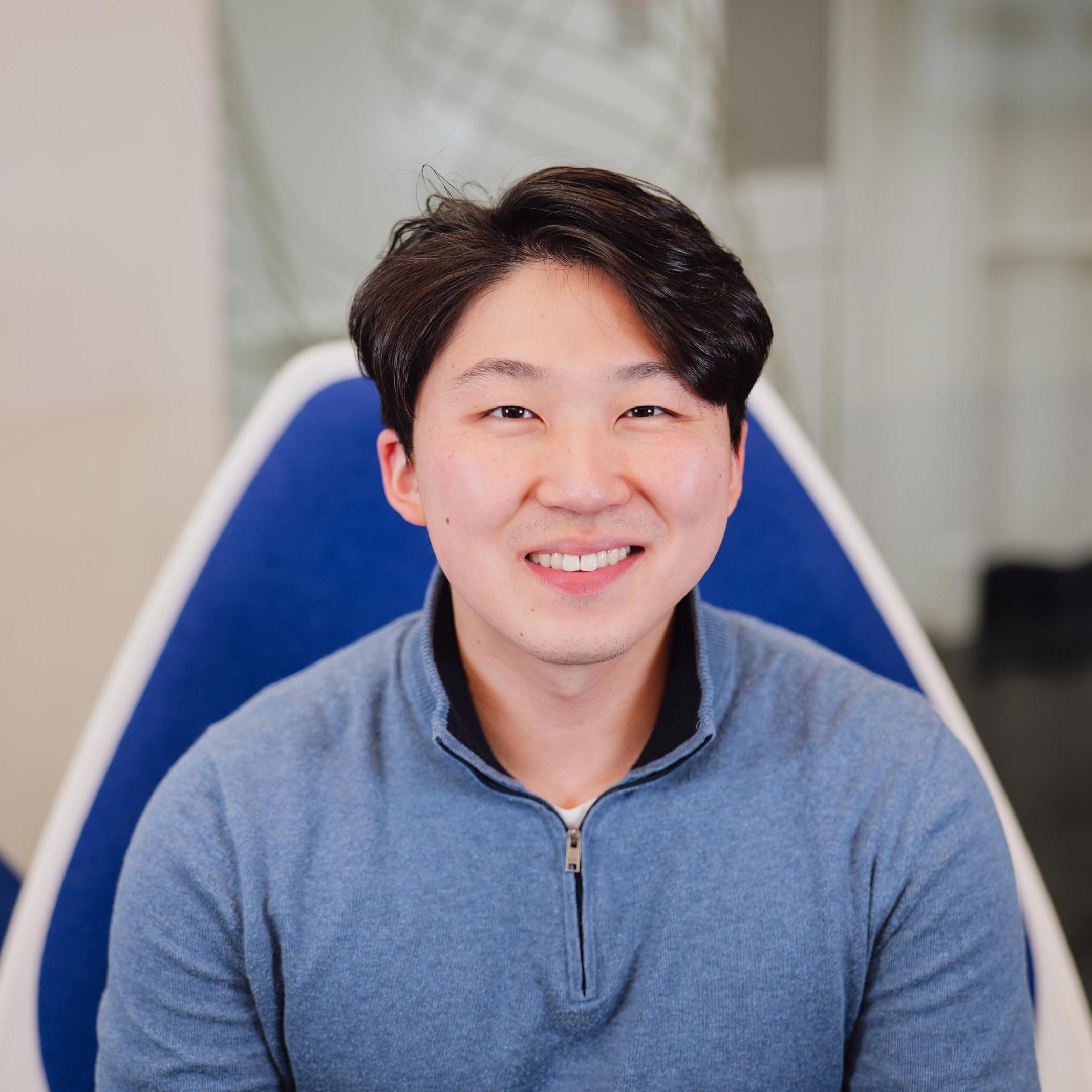 Portrait of Derek Lee sitting in a blue chair